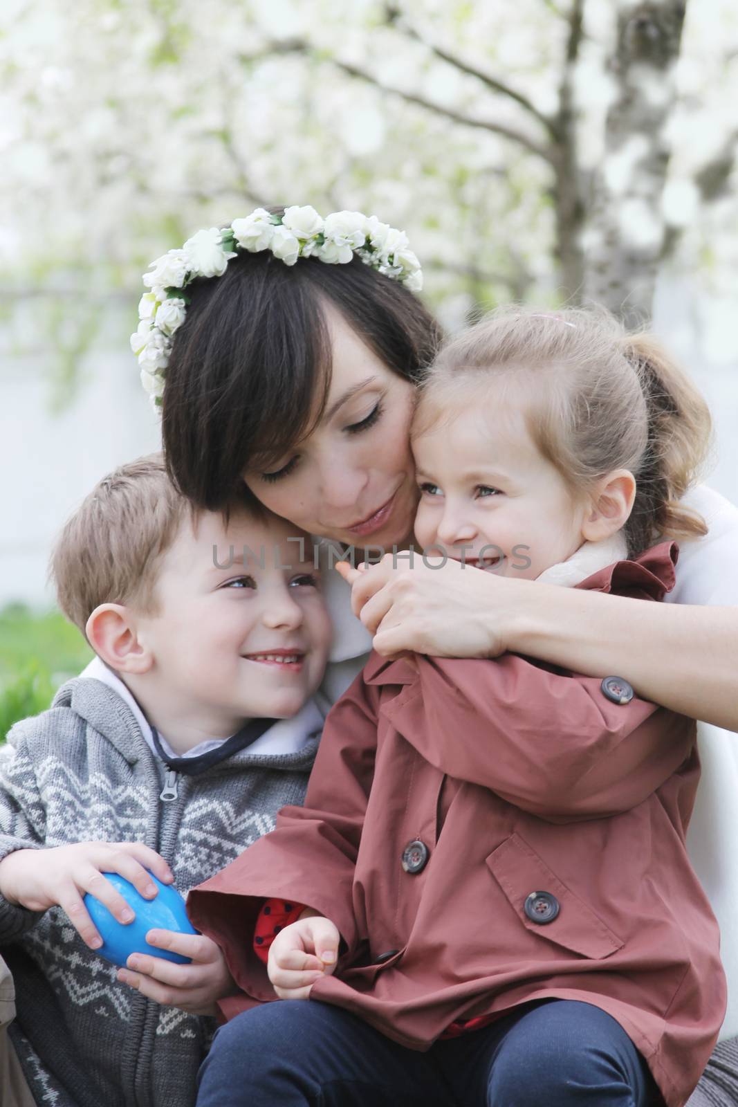 Mother and two children hugging among blooming garden by Angel_a