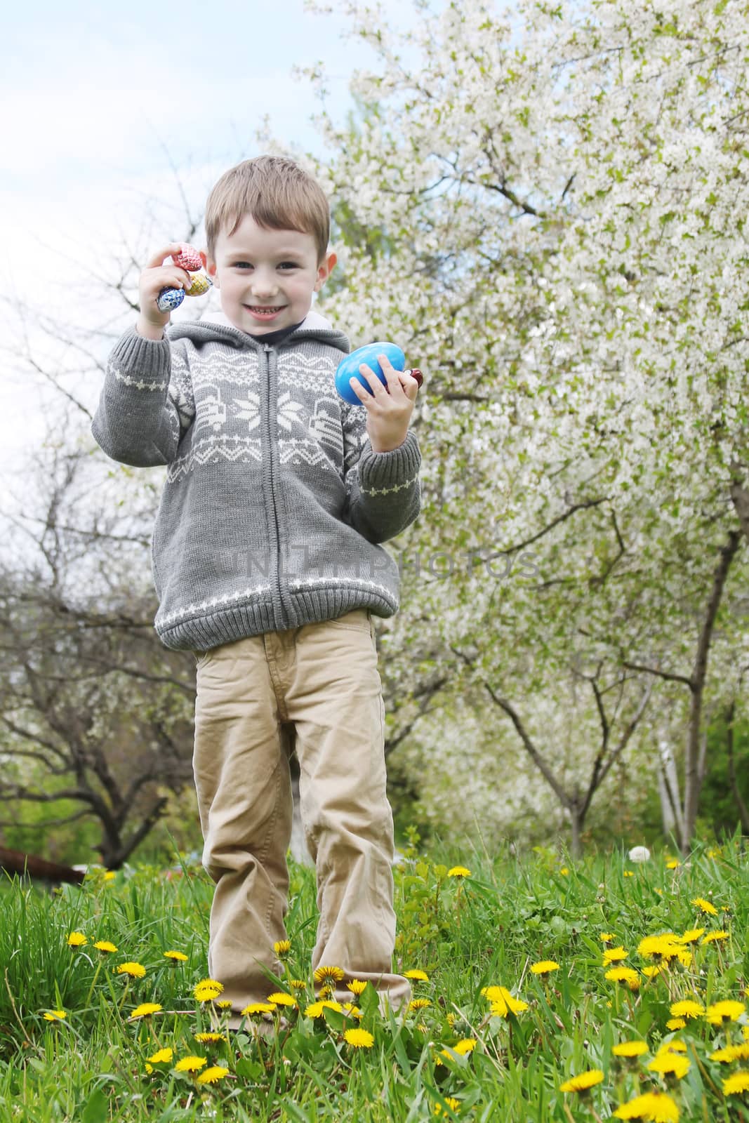 Happy boy searching Easter eggs among grass