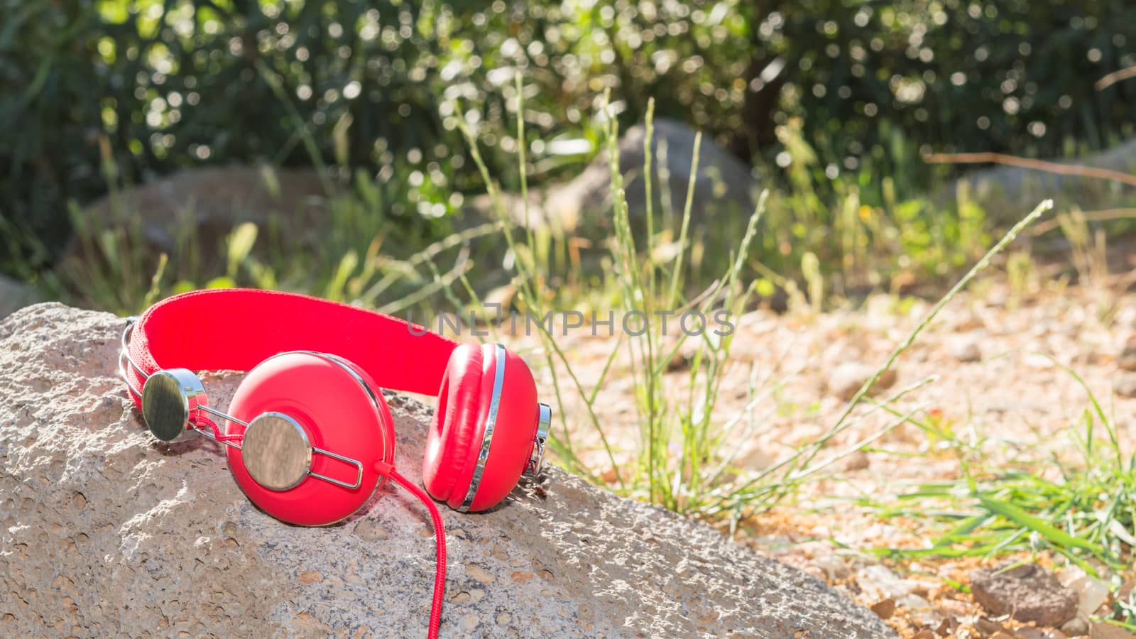 Bright red wired headphones on the rock with free place for your text