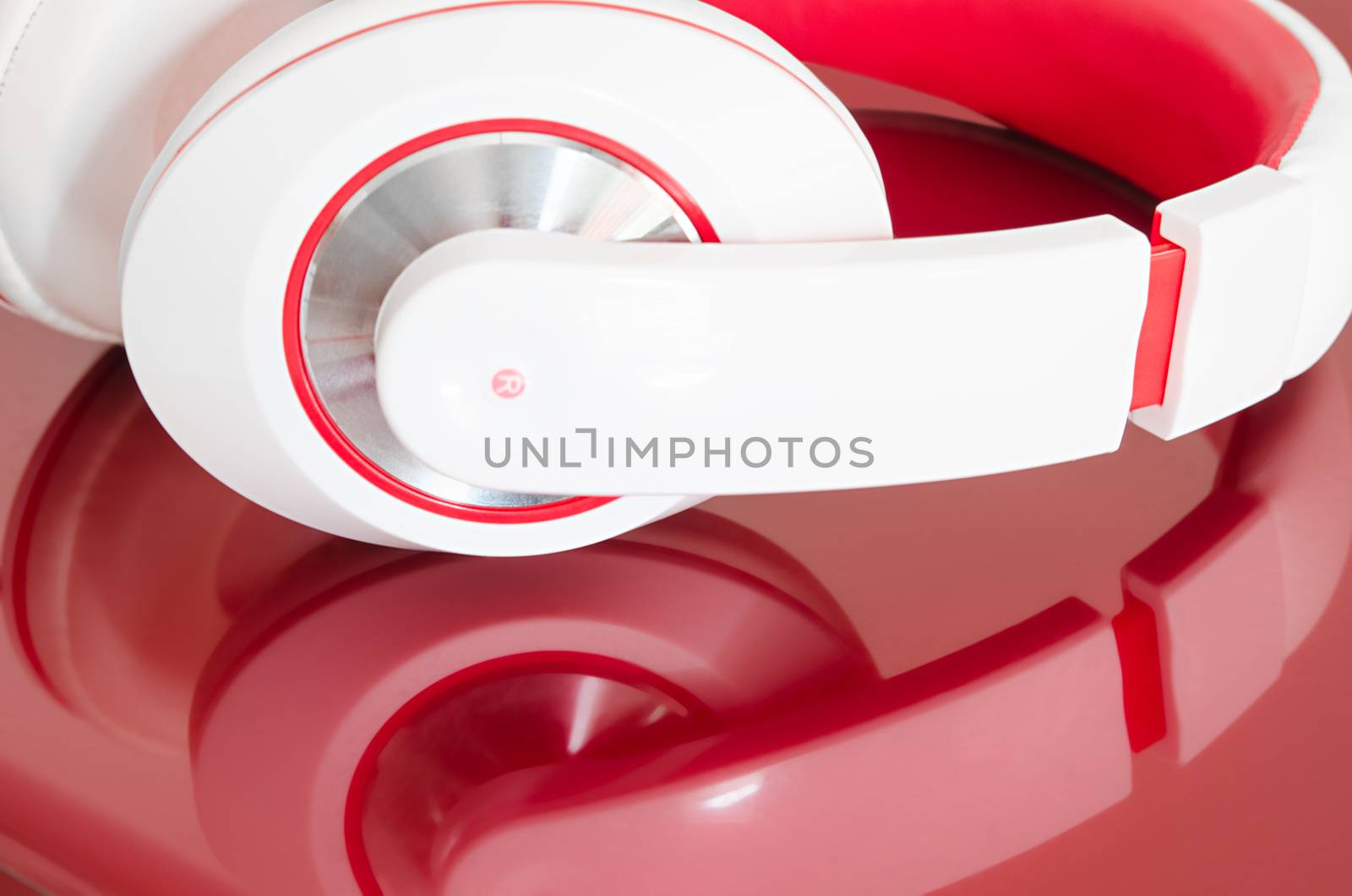 Red and white colorful headphones on bordo laptop mirrored surface