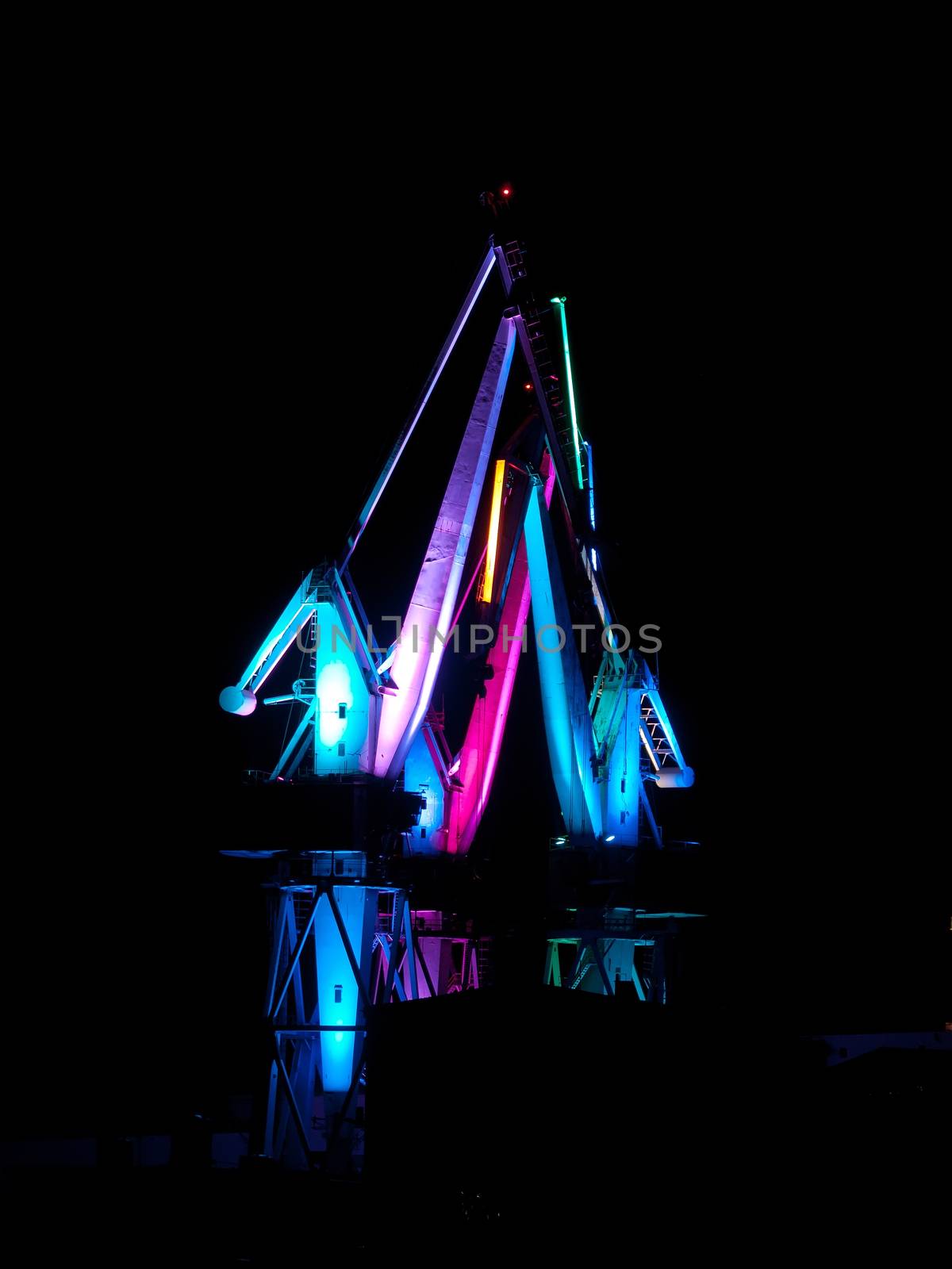 Shipyard cranes by night, multicolored illumination 