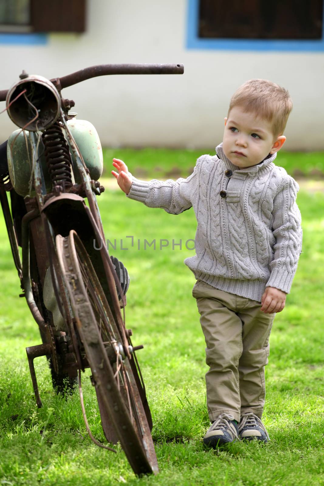 2 years old curious Baby boy walking around the old bike  by vladacanon