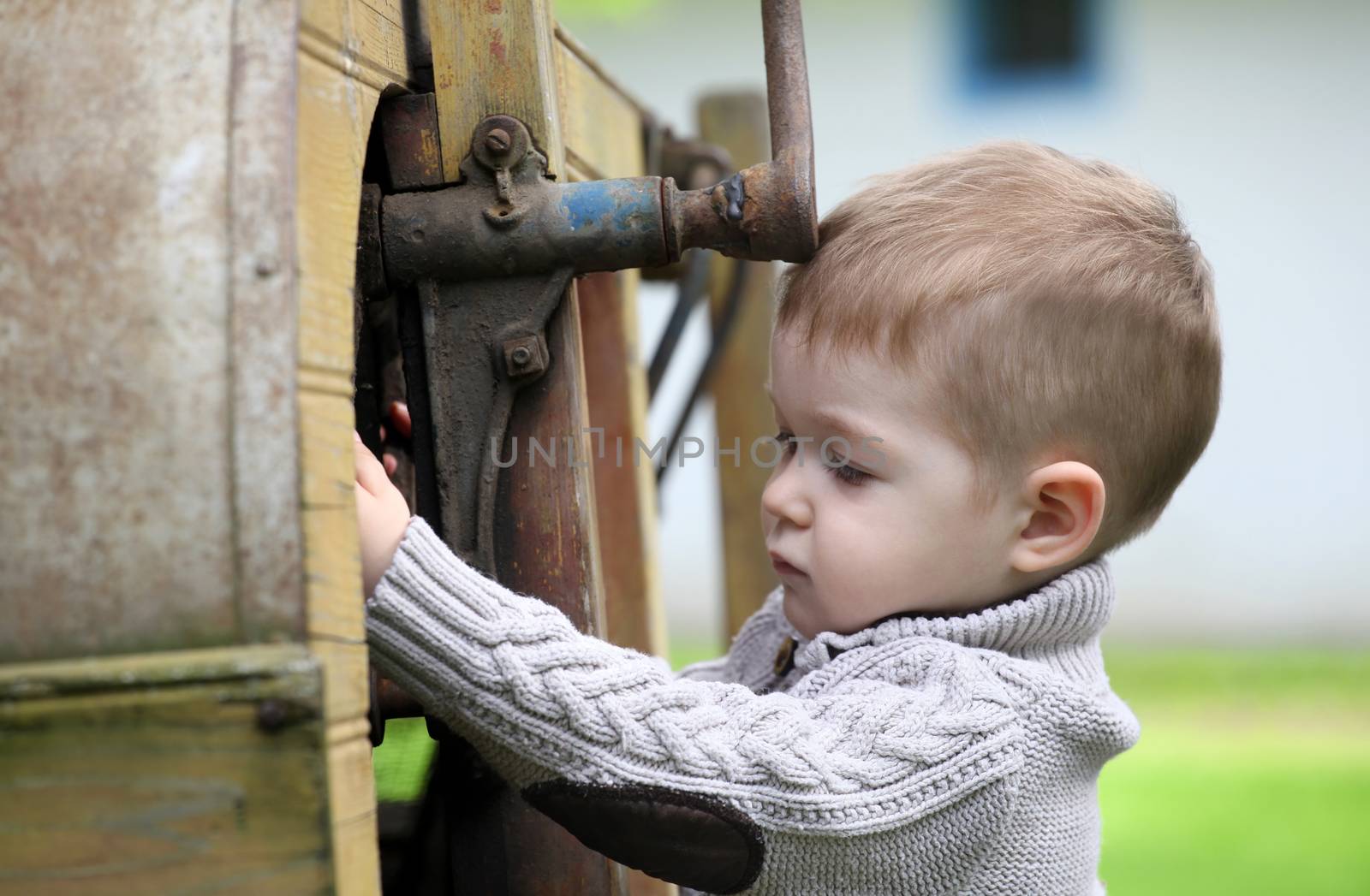 2 years old curious Baby boy managing with old agricultural Machinery