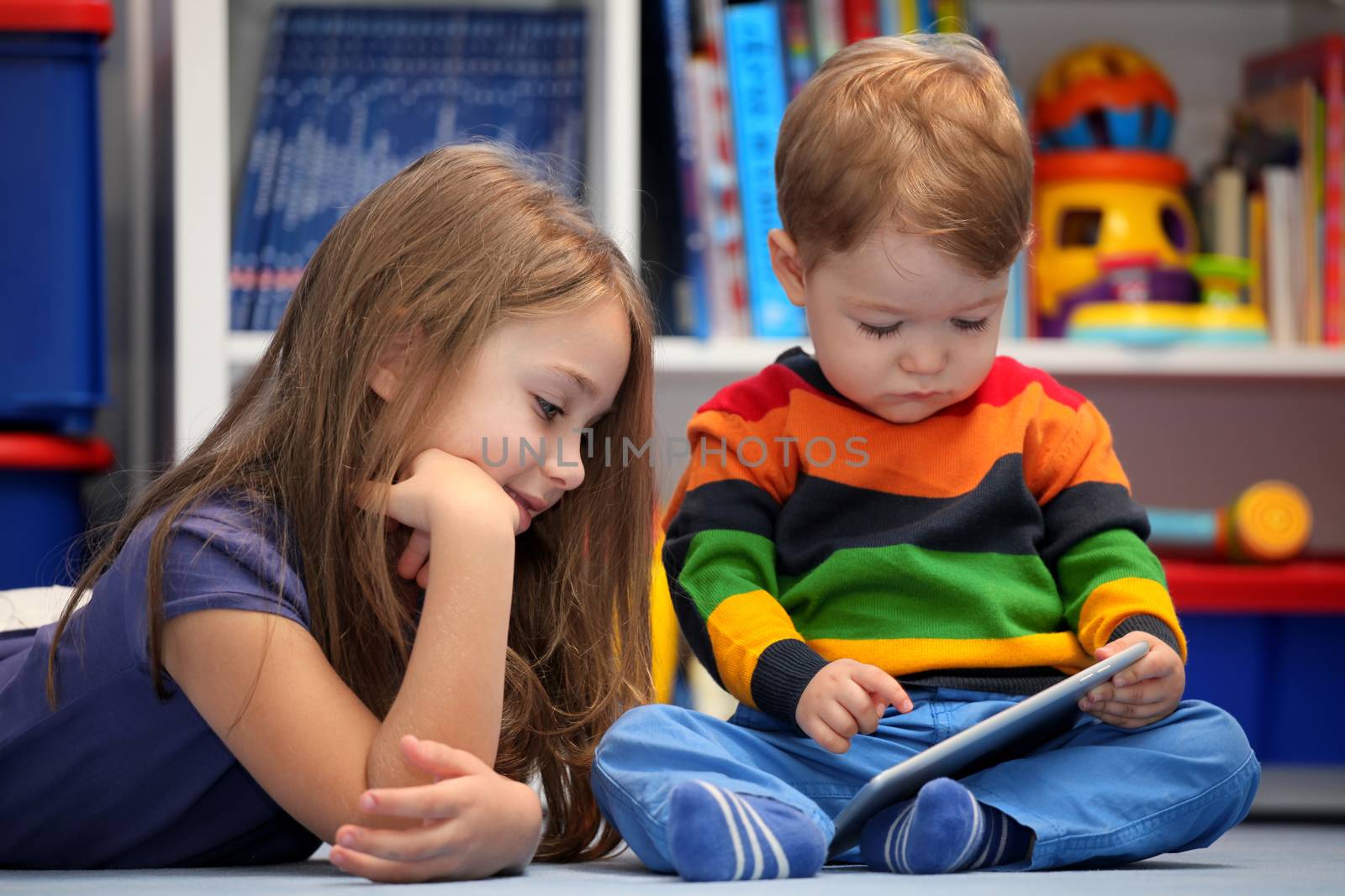 Girl with her little brother fun using a digital tablet computer by vladacanon