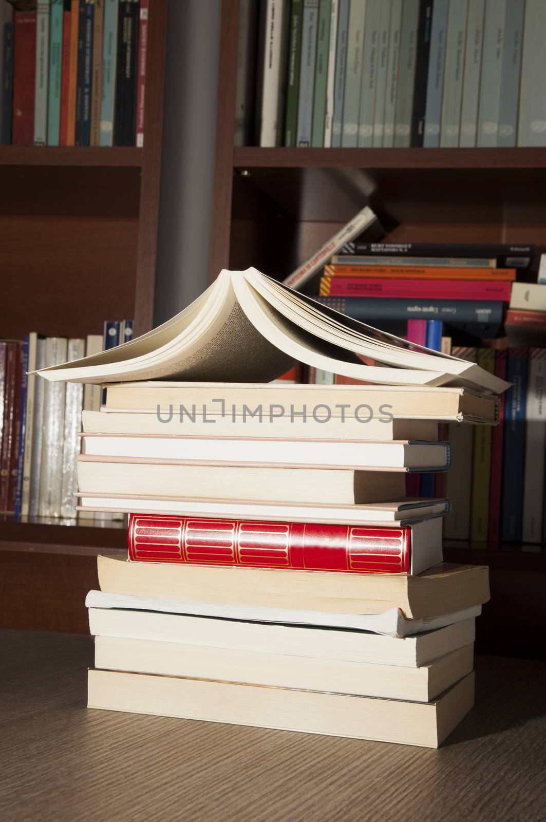 Books over wooden table, with bookshelves on the back