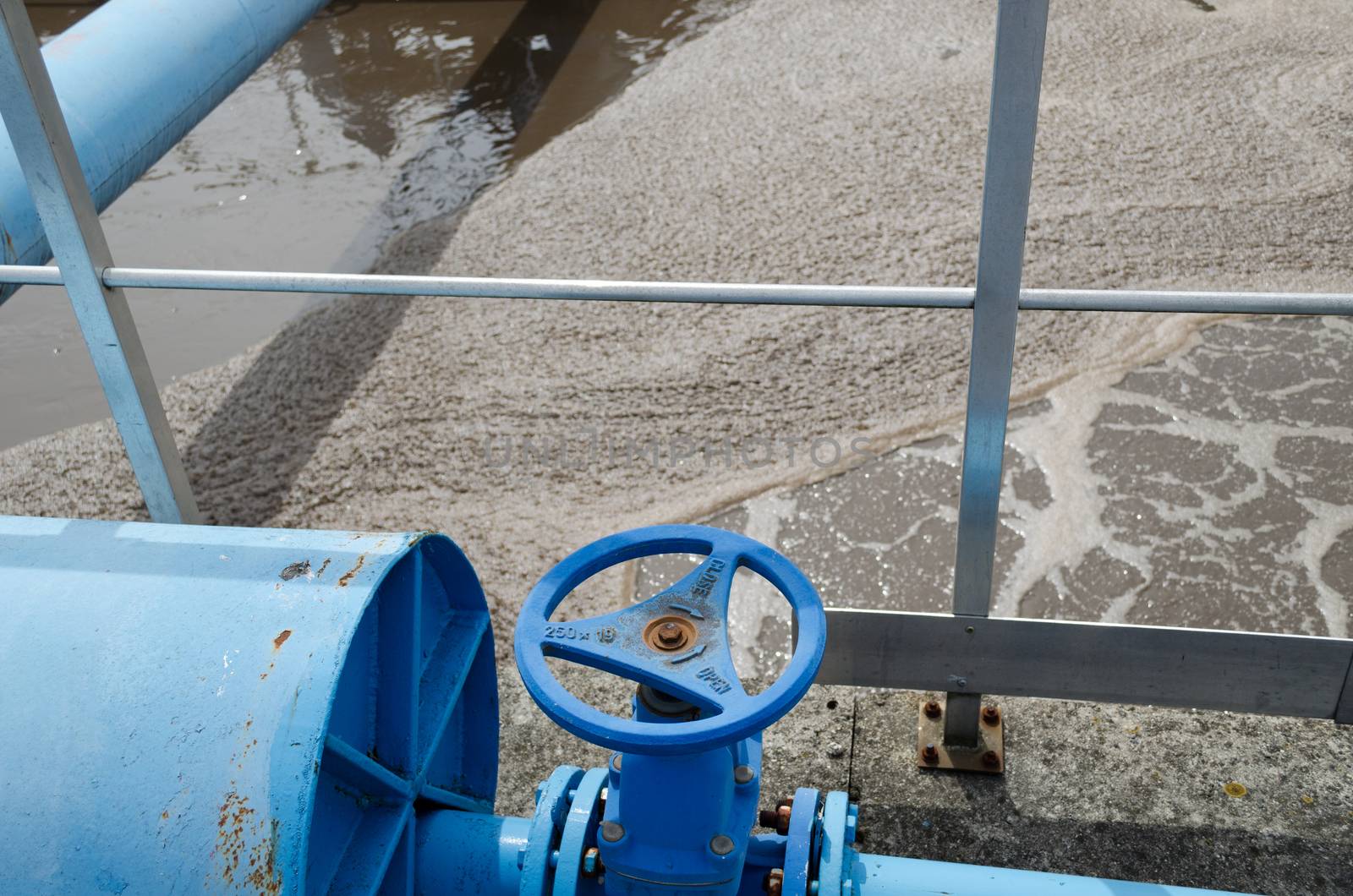 Panorama of blue valve gate stopcock for oxygen blowing in sewage water and pipes in treatment plant and dirty liquid bubble.