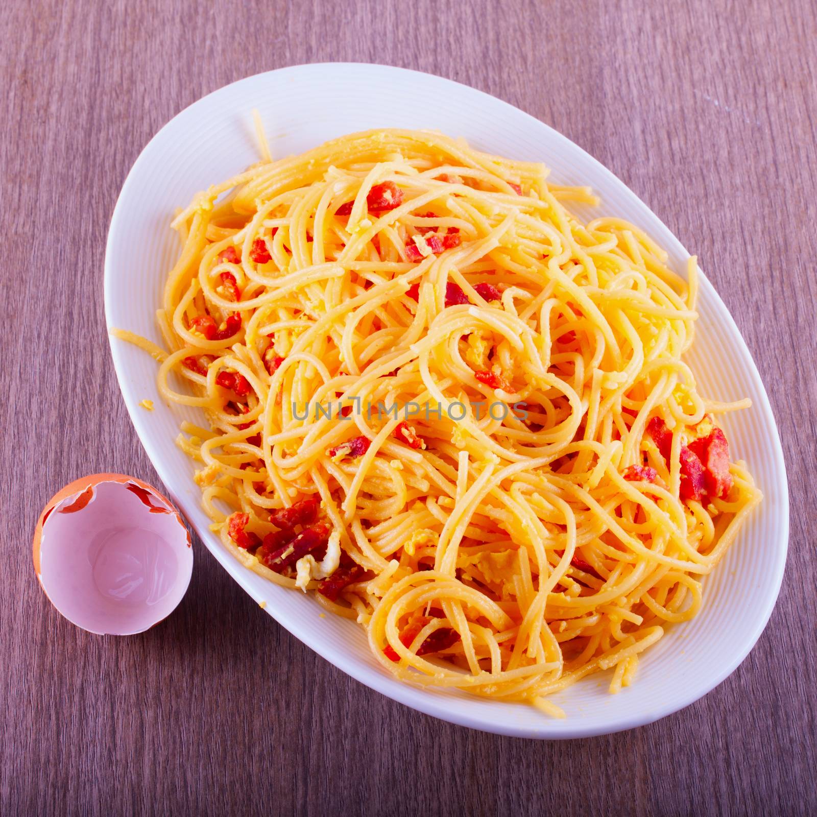 Spaghetti alla carbonara, over wooden table, with eggshell