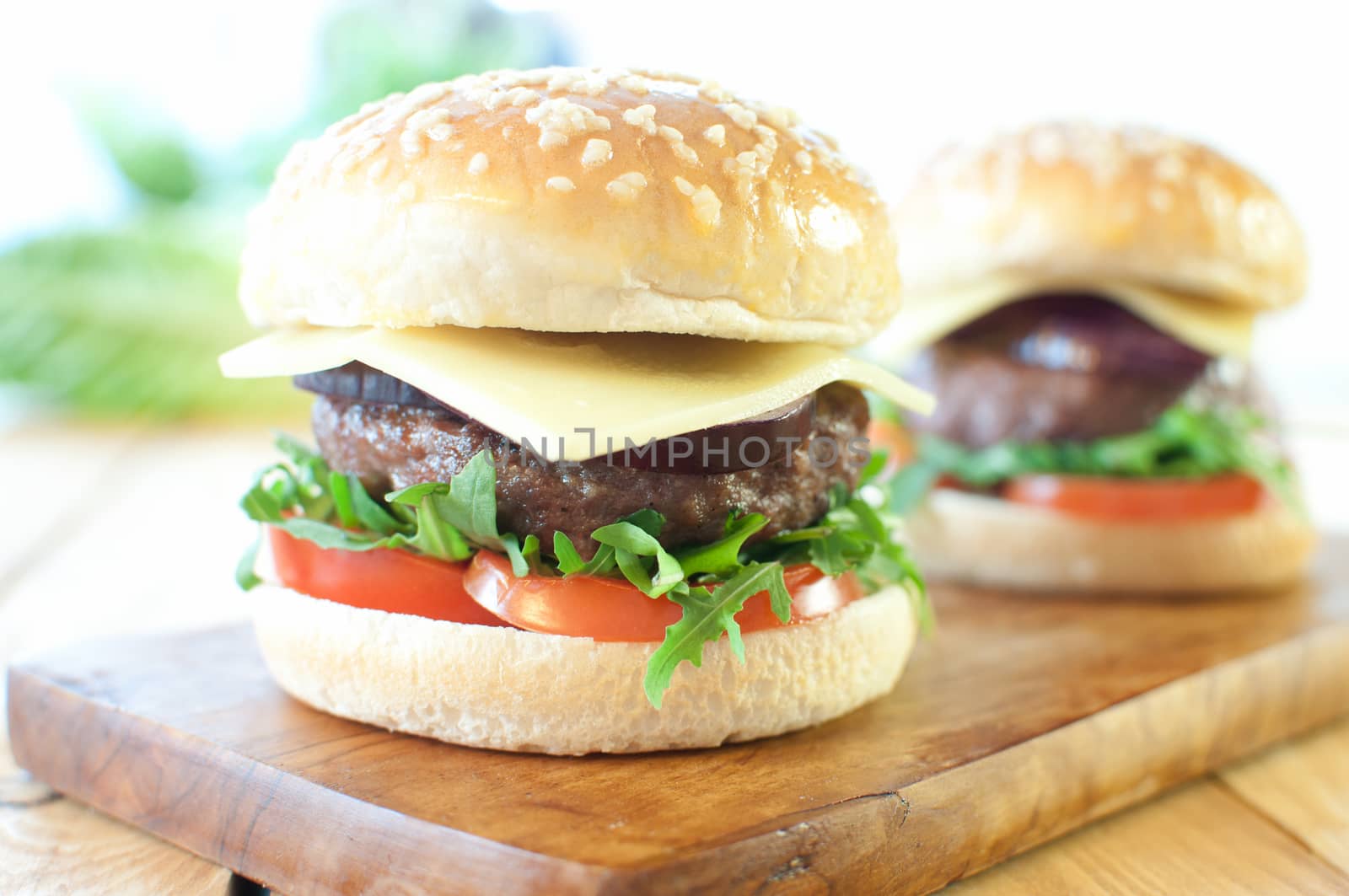 Freshly made hamburgers with tomatoes, red onion and cheese 