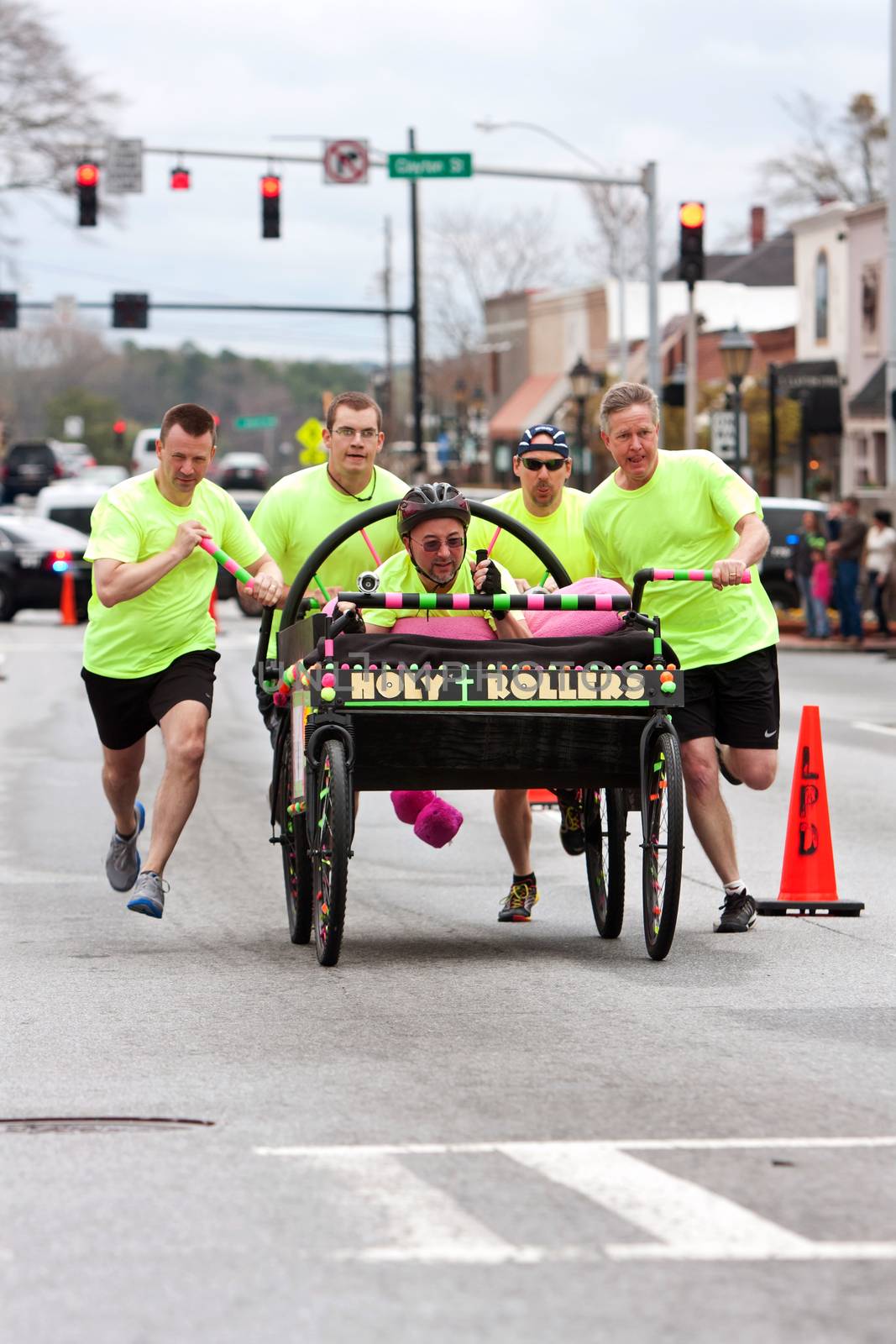 Lawrenceville, GA, USA - March 29, 2014:  A team of clergymen pushes a "Holy Rollers" bed down a street in the annual Lawrenceville Bed Race, to benefit a local Gwinnett County homeless shelter.