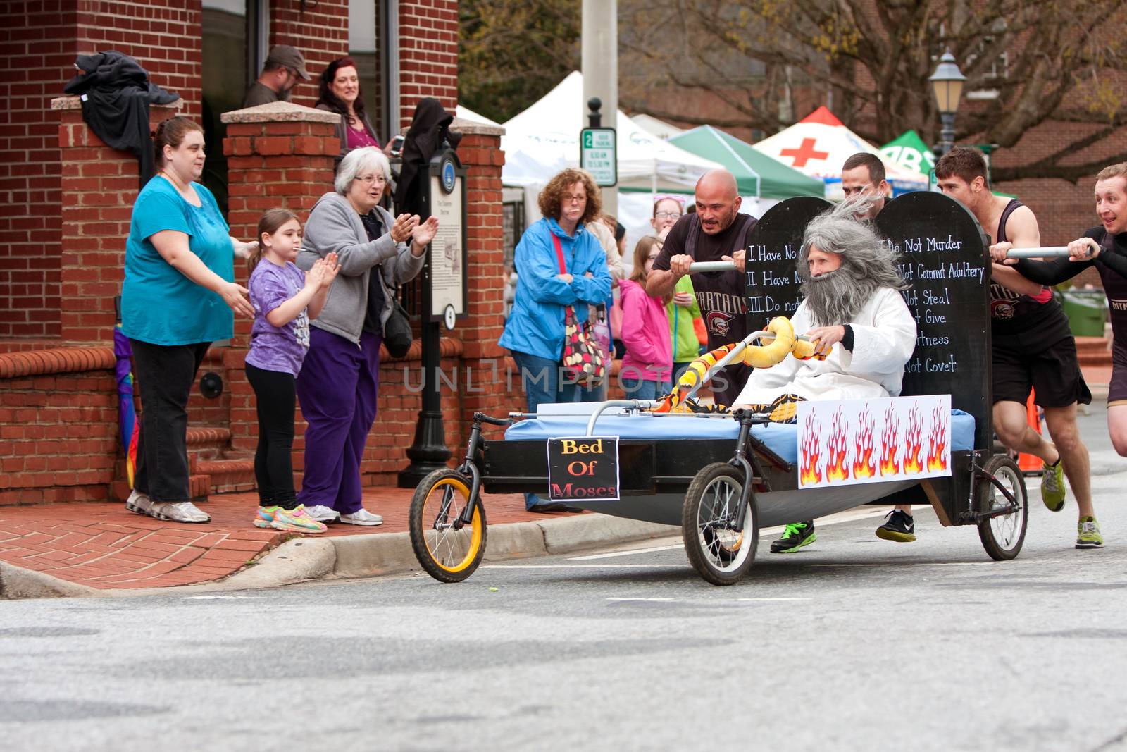 Lawrenceville, GA, USA - March 29, 2014:  A team pushes the "bed of Moses" around a corner in the annual Lawrenceville Bed Race, to benefit a local Gwinnett County homeless shelter.