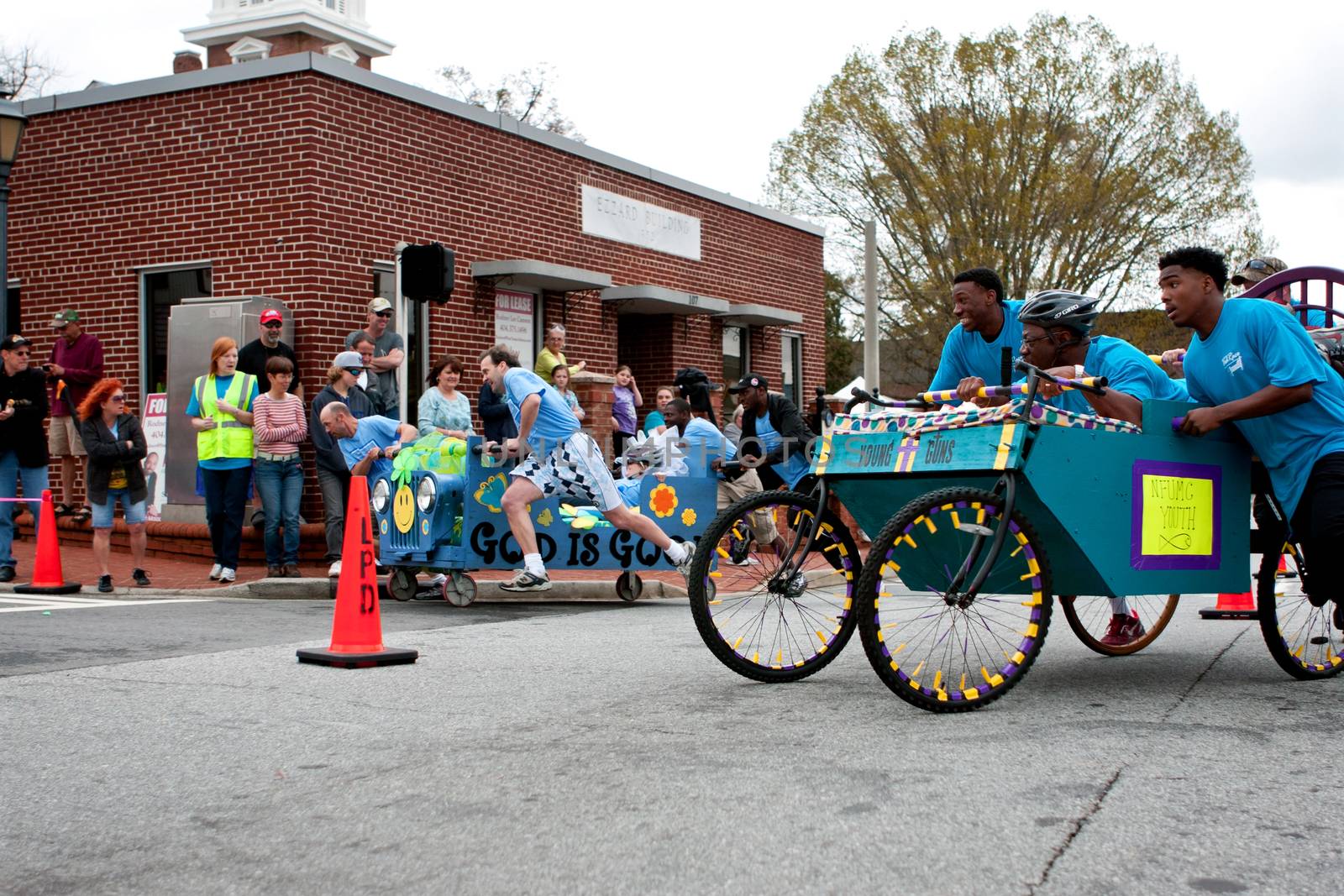 Lawrenceville, GA, USA - March 29, 2014:  Two teams push silly looking beds around a downtown street corner in the annual Lawrenceville Bed Race, to benefit a local Gwinnett County homeless shelter.