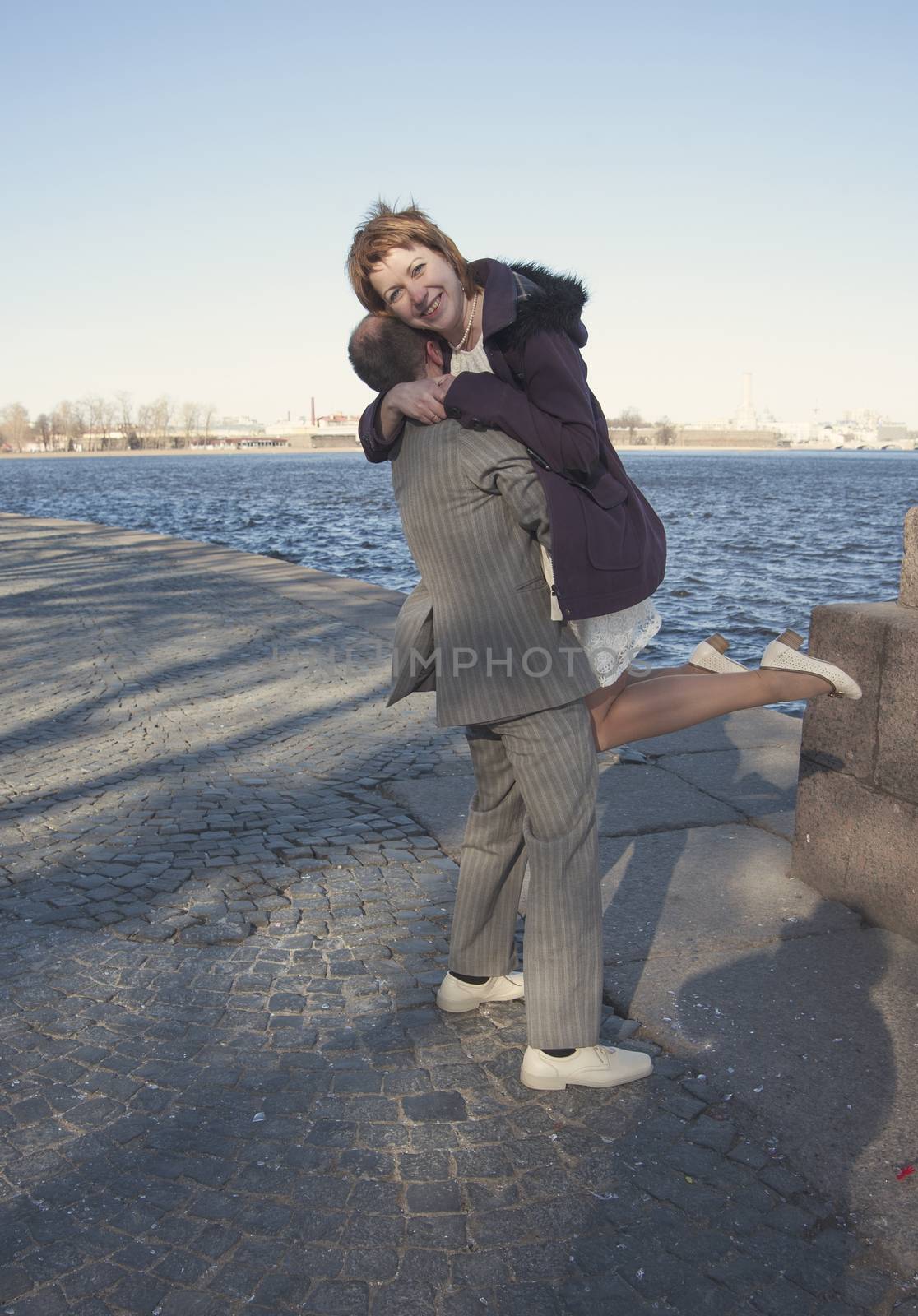 couple walk along the embankment of the river