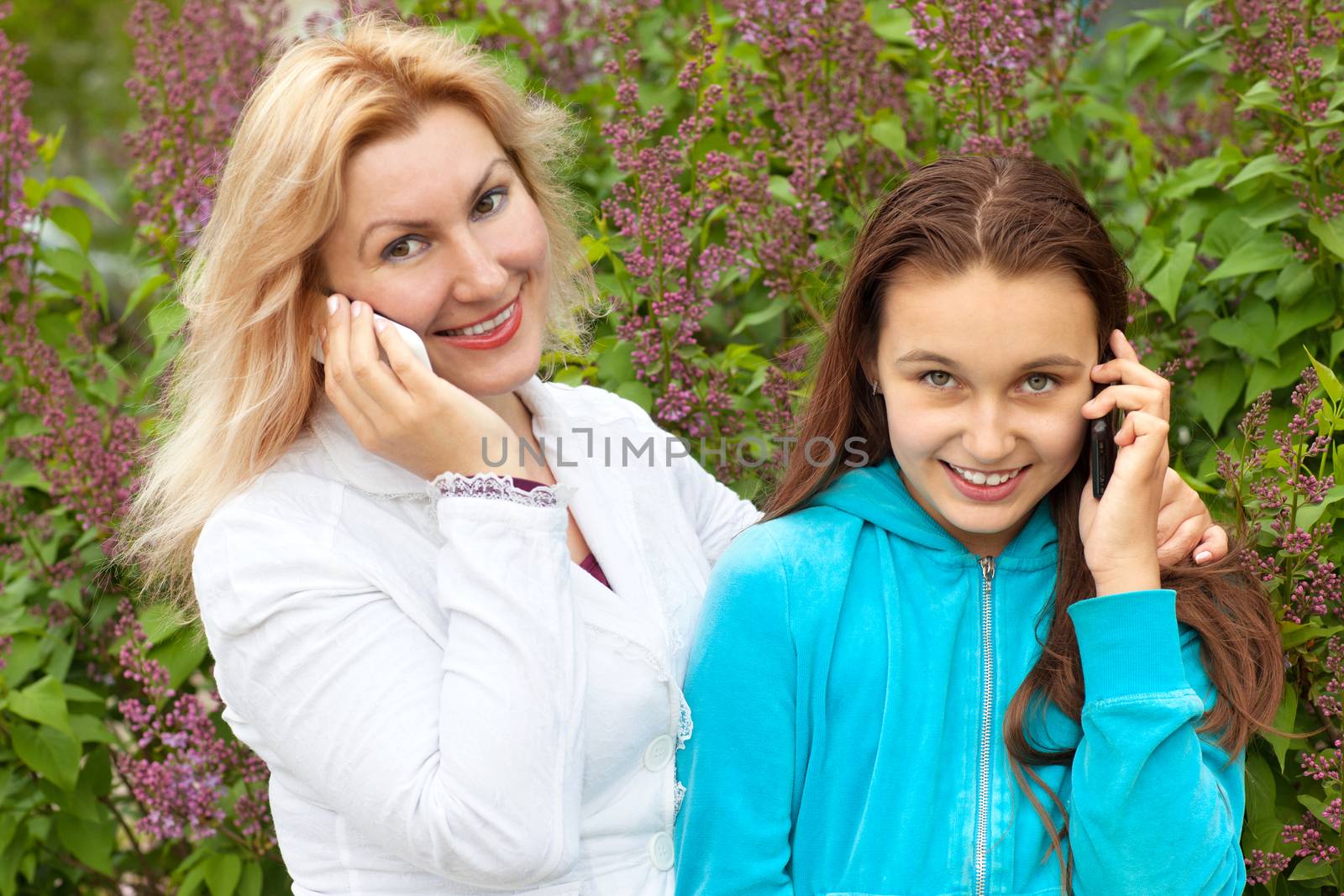 mom and daughter talking by phones by vsurkov