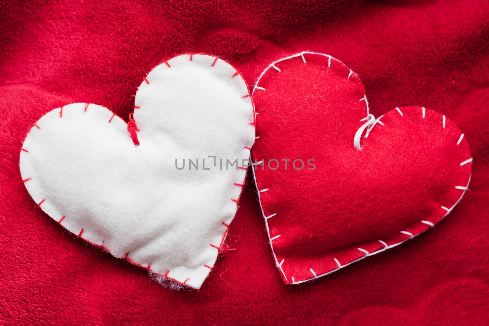 Handmade plush red hearts couple on soft blanket. Romantic love, Valentine's Day concepts.