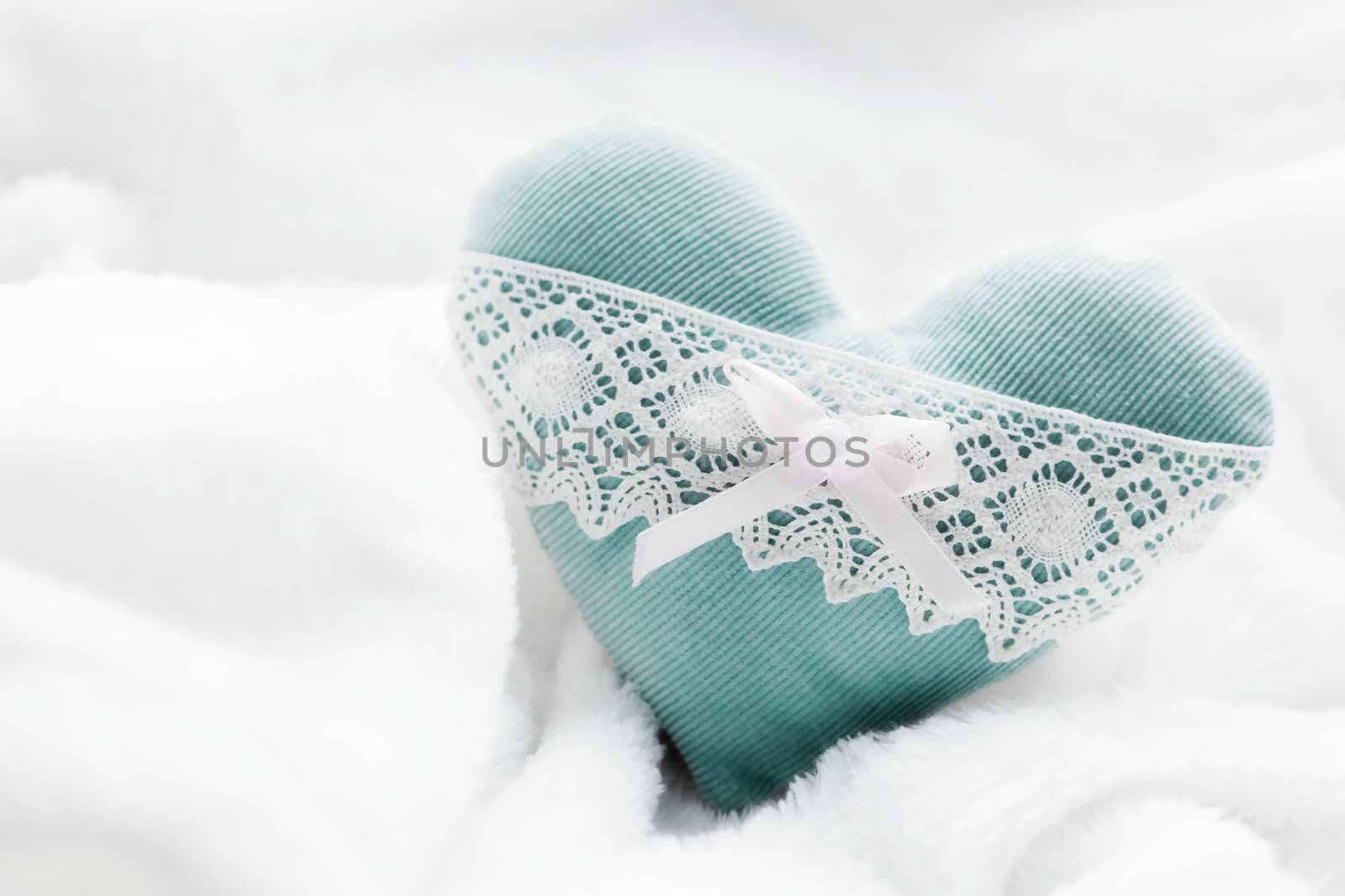 Vintage handmade plush turquoise heart on the soft white blanket. Romantic love, Valentine's Day concepts.