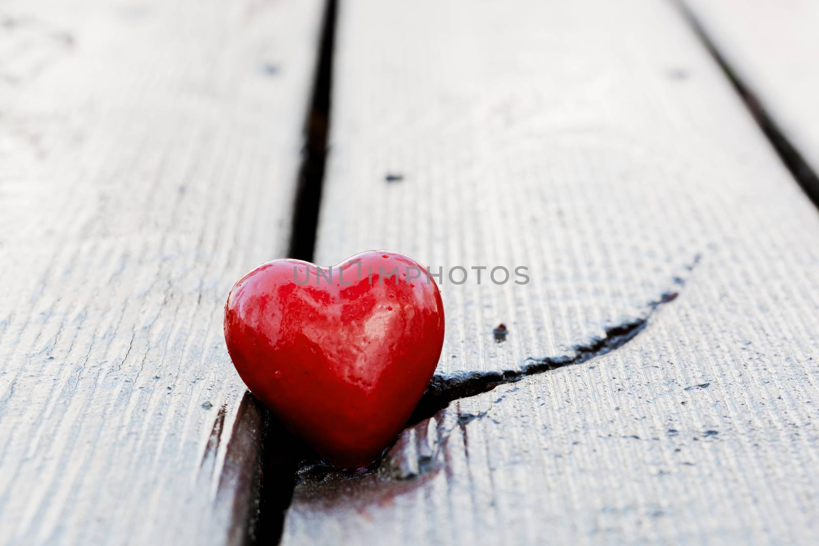 Red heart in crack of wooden plank. Symbol of love, Valentine's Day, a crack may symbolize a broken heart.