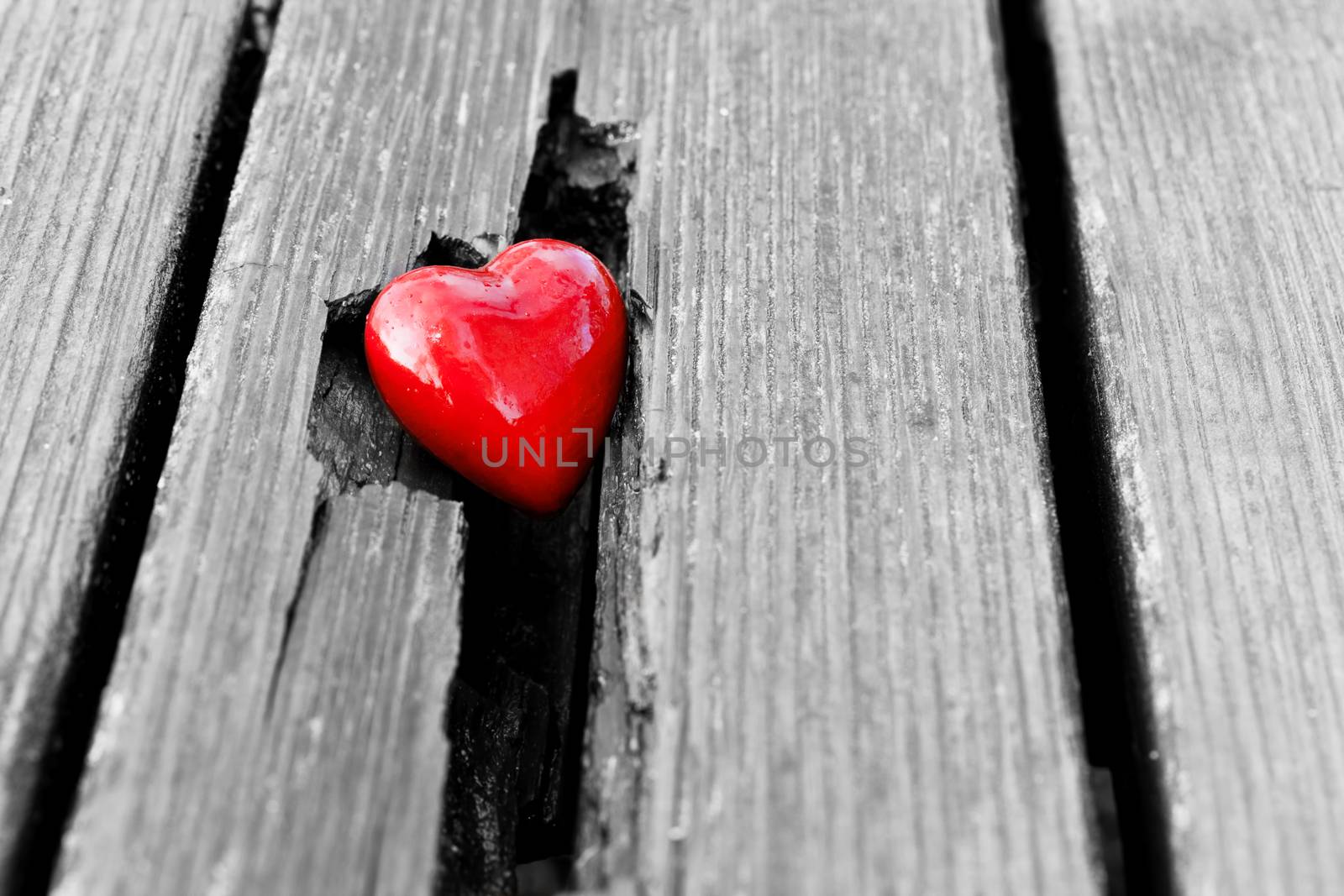 Red heart in crack of wooden plank. Symbol of love by photocreo