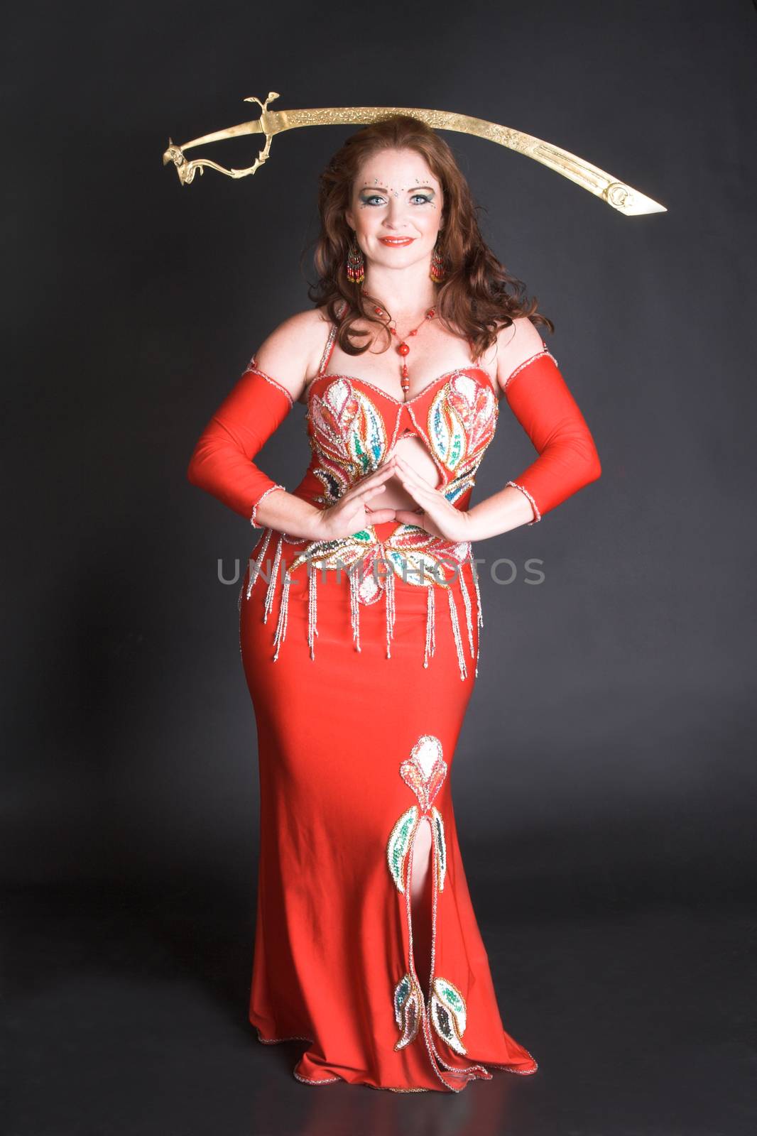 Belly Dancer in red costume balancing a tribal sword