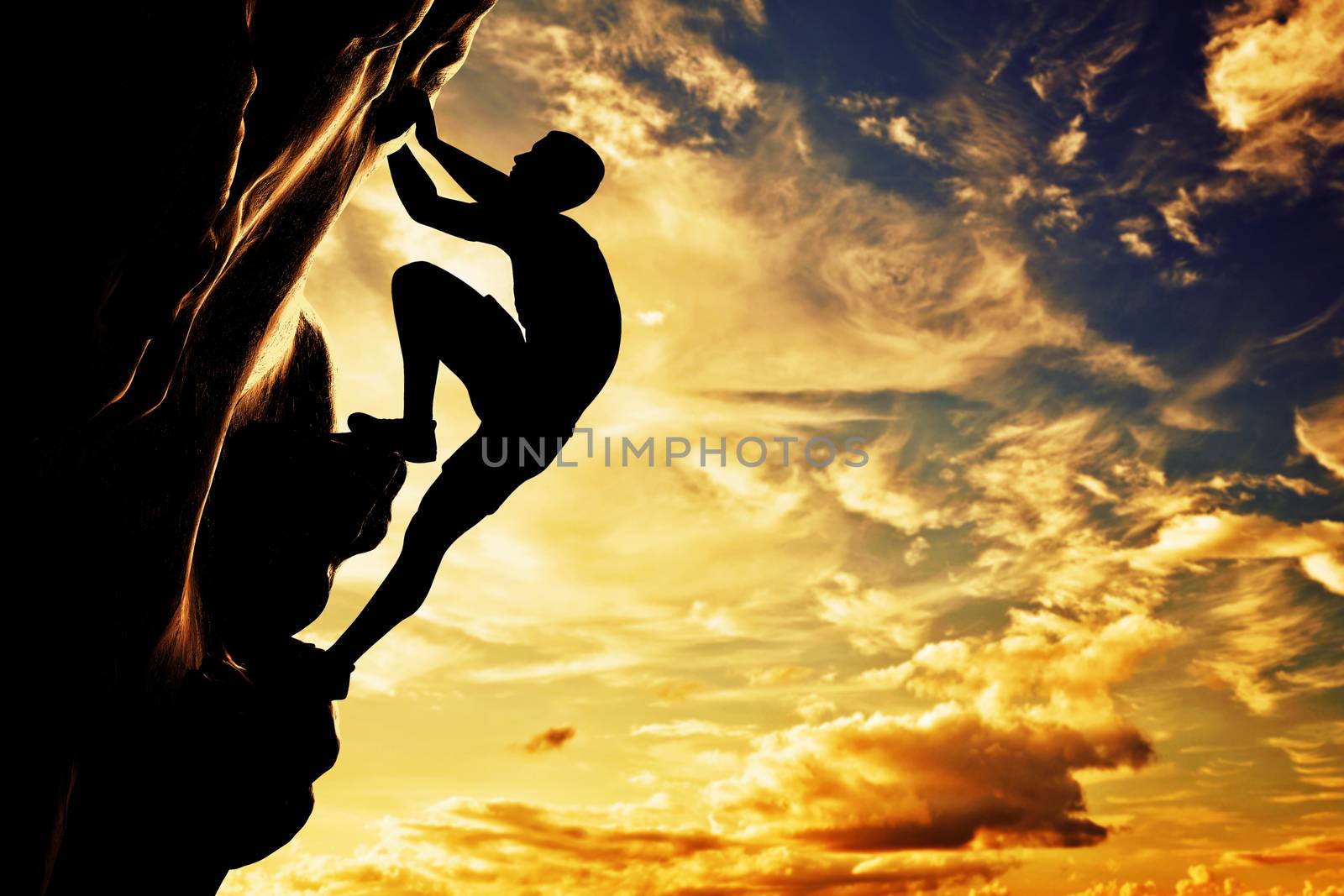 A silhouette of man free climbing on rock, mountain at sunset. Adrenaline, bravery, leader.