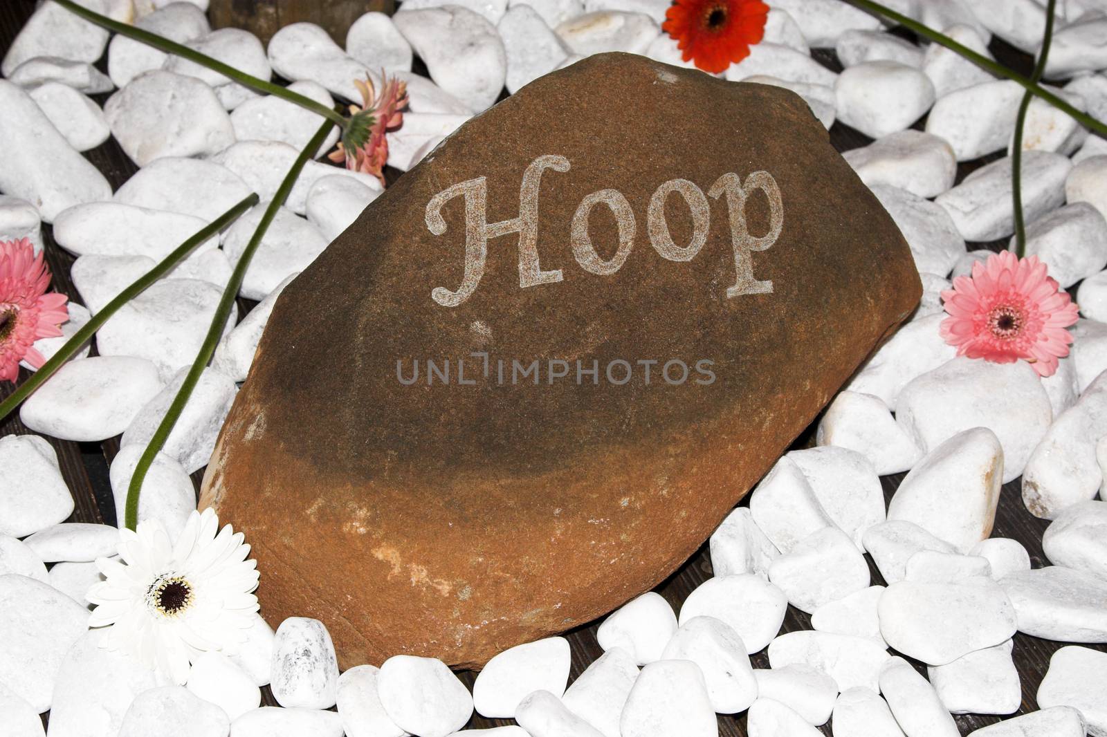 Small sign amongst pebbles with an afrikaans word meaning Hope