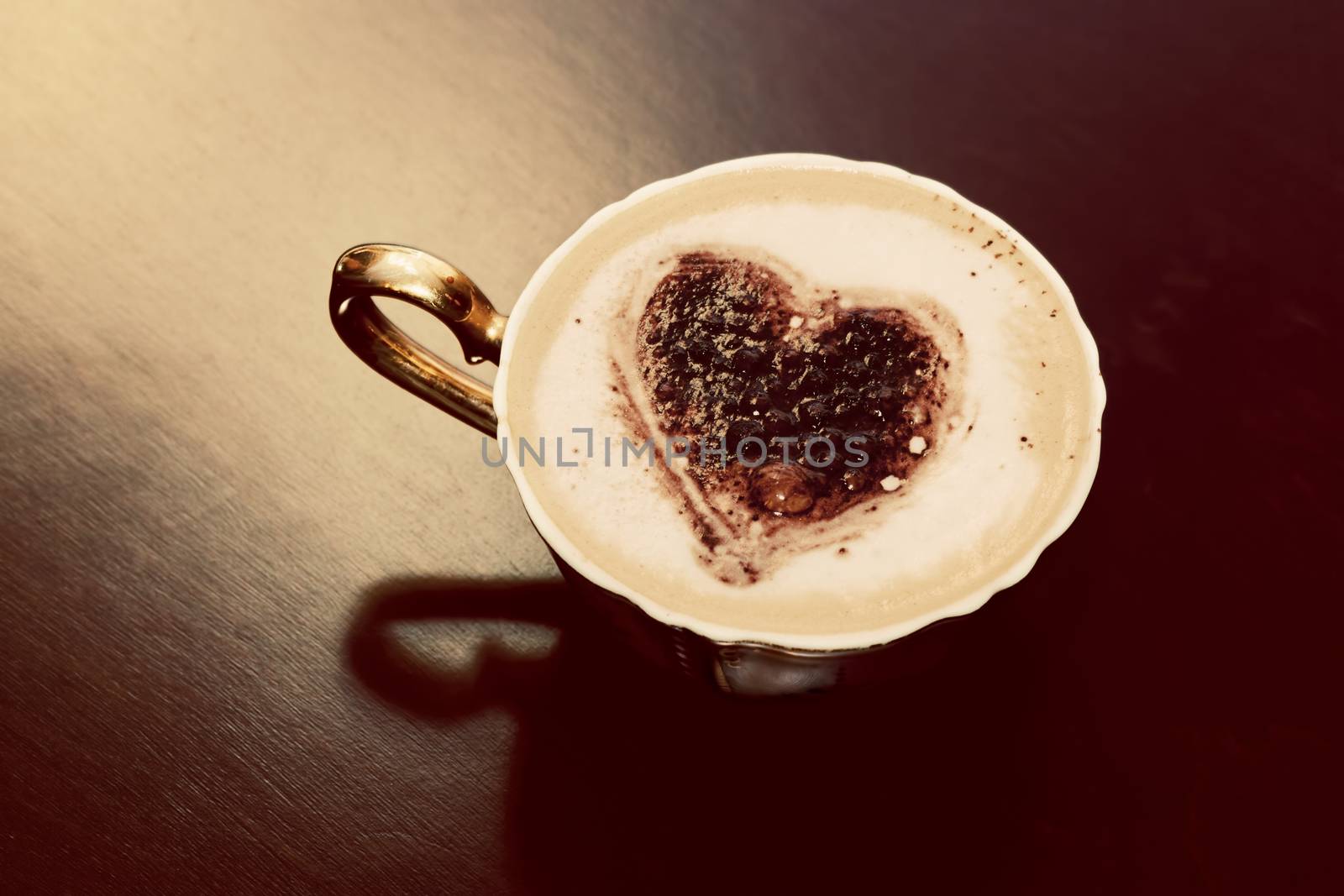 Cup of coffee with chocolate heart shape on milk foam. Romantic morning light. Vintage