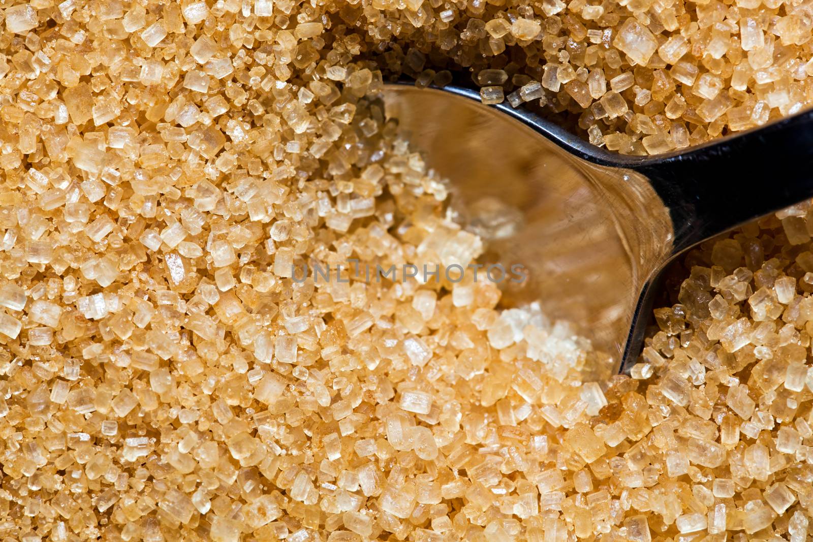Brown, unrefined sugar and a silver spoon in it by photocreo