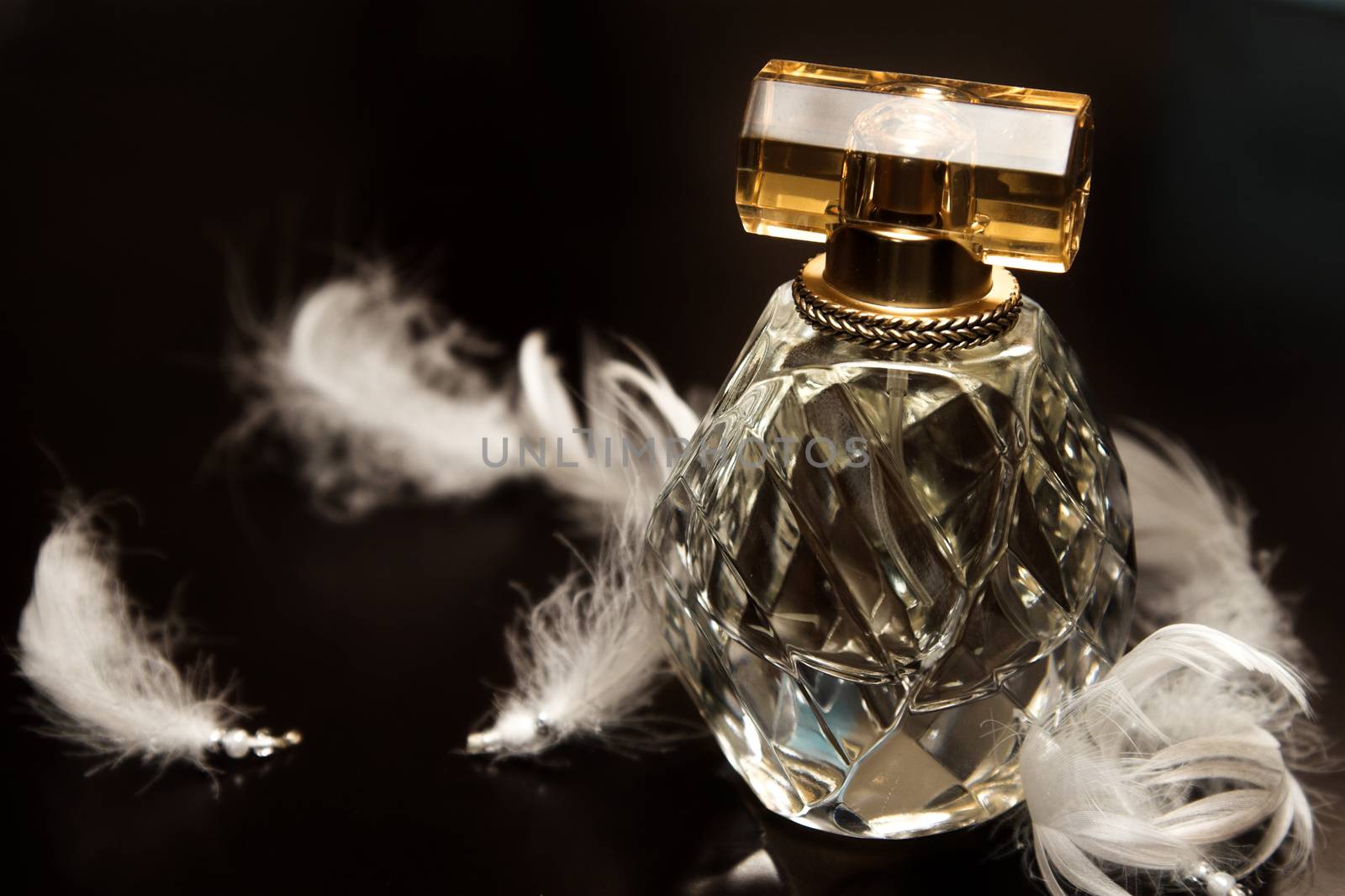 Glass perfume bottle amongst white beaded feathers