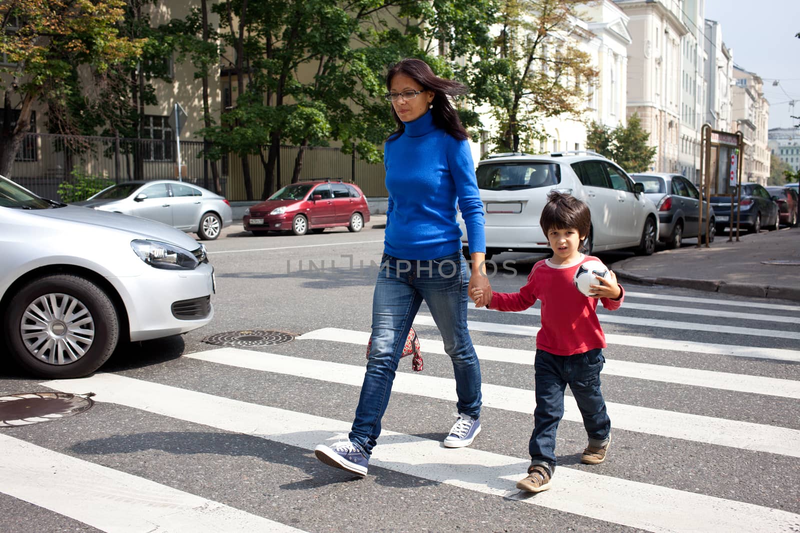 Mother and son are on a pedestrian crossing in the city