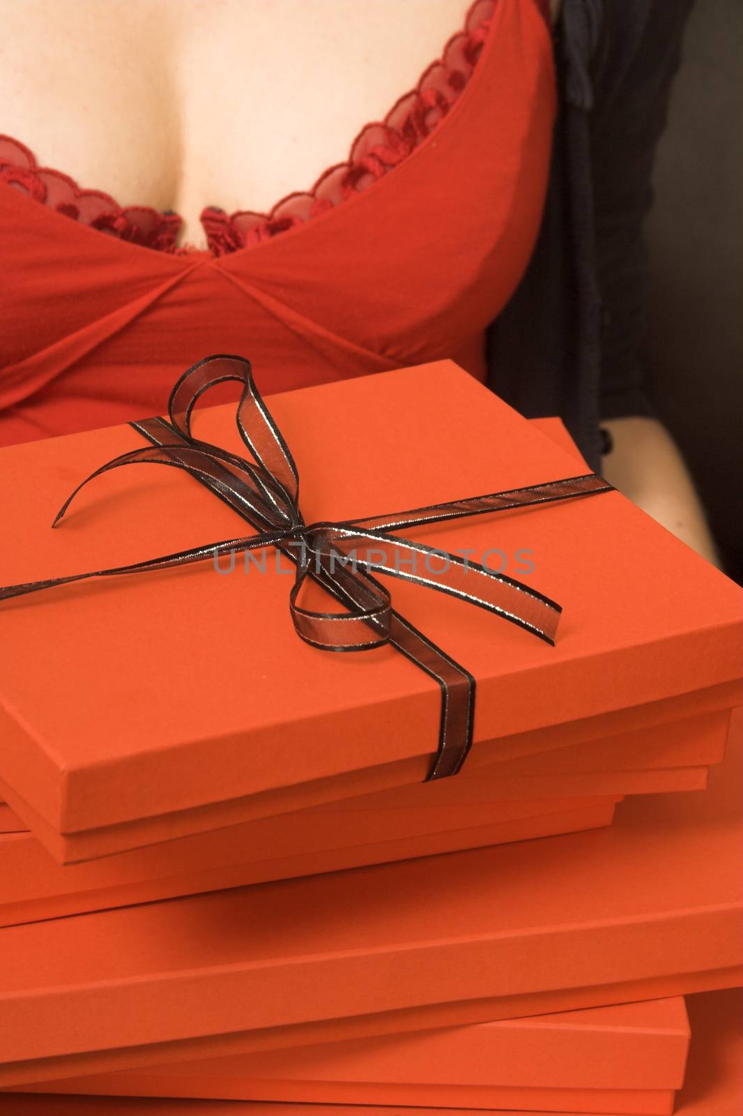 A stack of red gift boxes, the top one tied with black ribbon