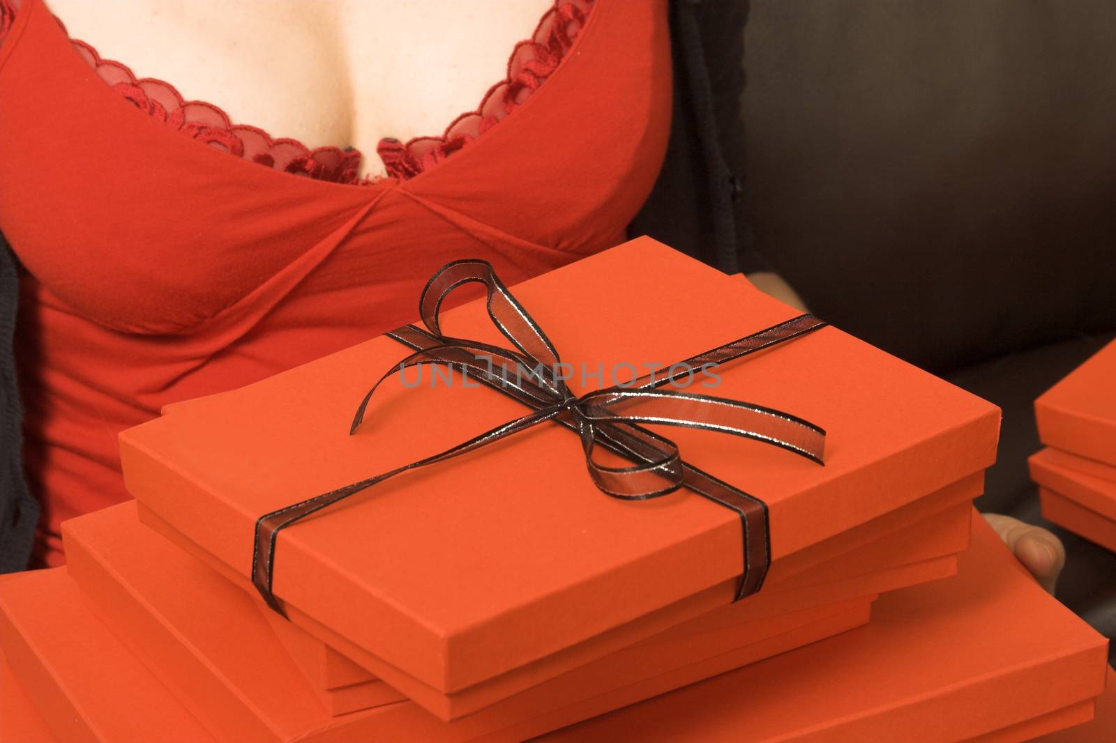 A stack of red gift boxes, the top one tied with black ribbon