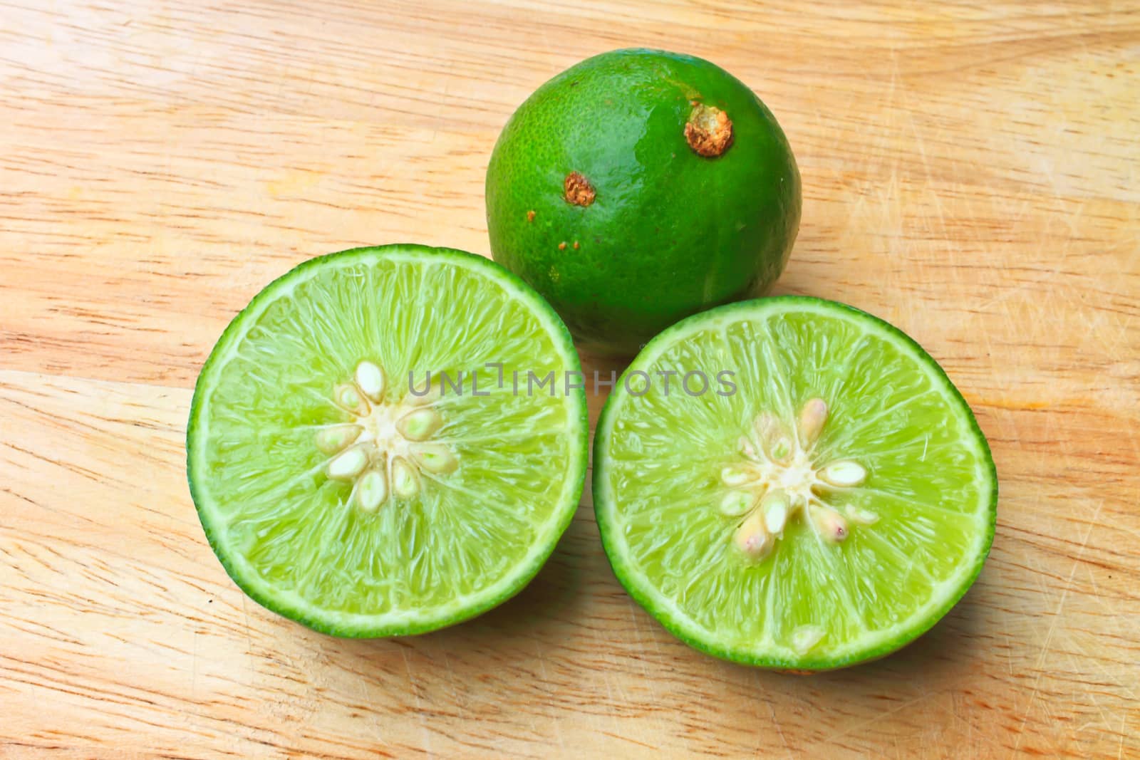 Fresh organic cut limes on wooden cutting board