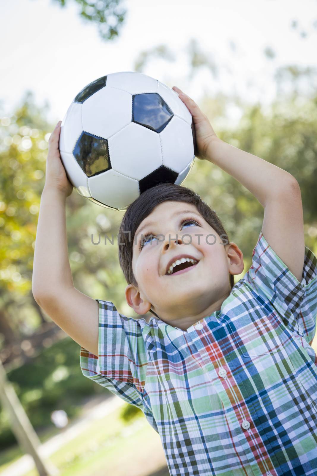 Cute Young Boy Playing with Soccer Ball Outdoors in the Park.