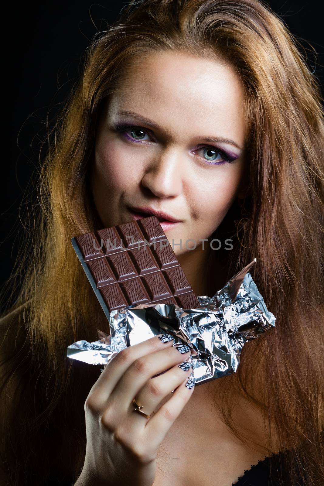 portrait of young girl with beautiful make eating chocolate