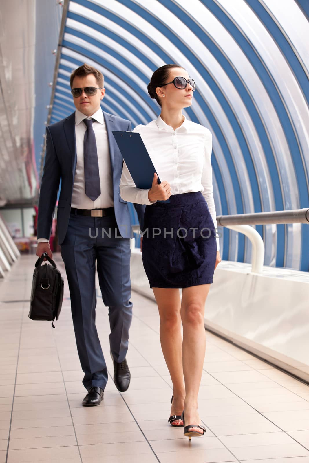 businesswoman and businessman walk down the hall in the business center