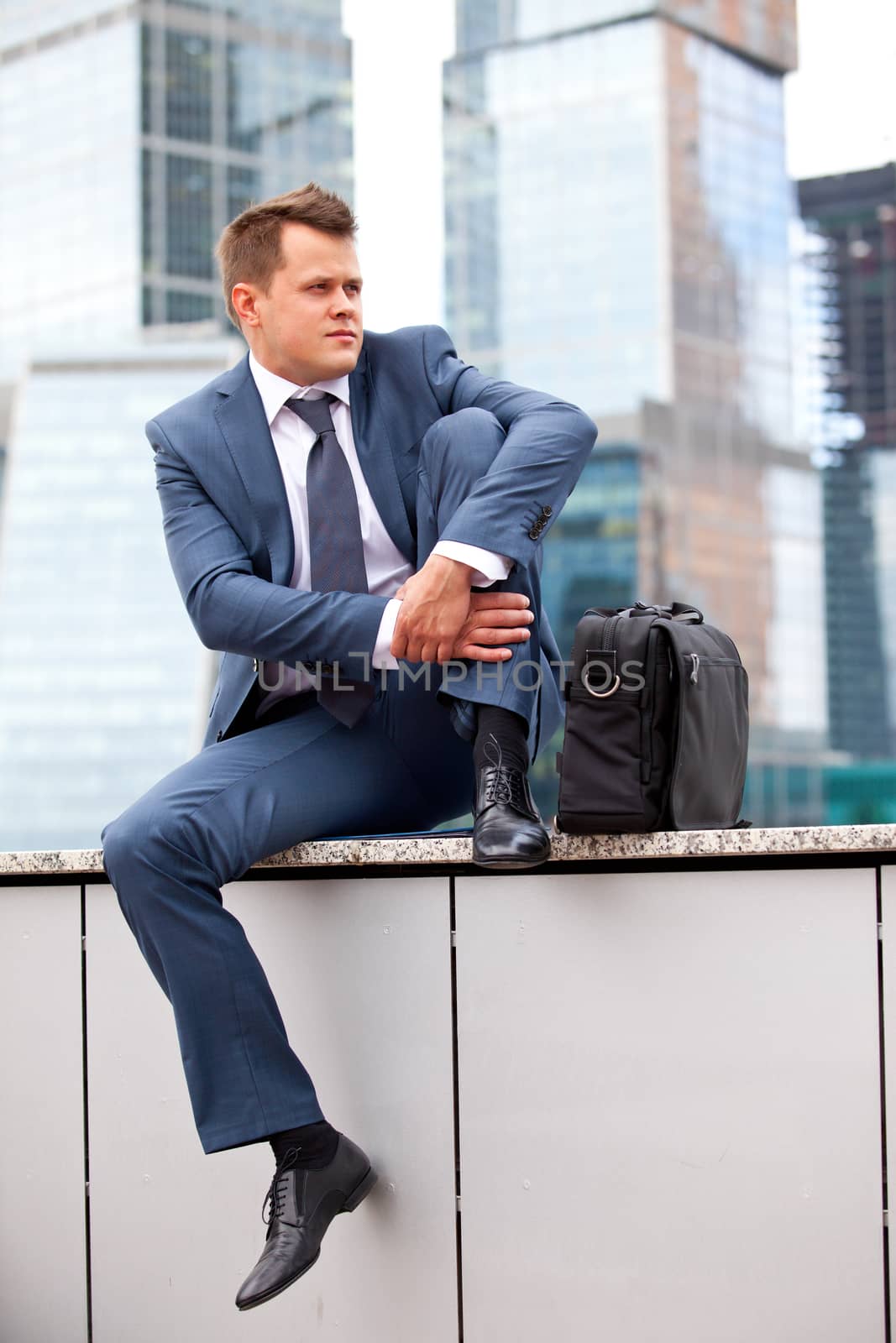 successful businessman resting on a background of office buildings