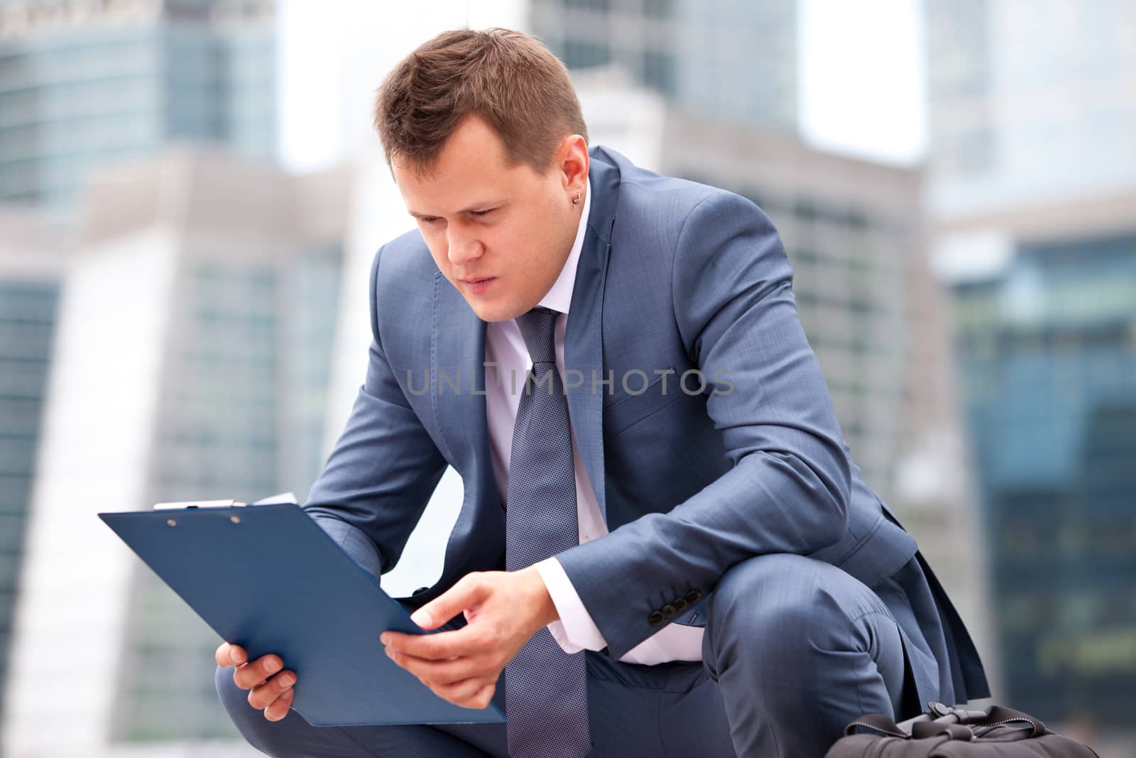successful businessman sitting on his haunches and holding a planning and looking thoughtfully at him