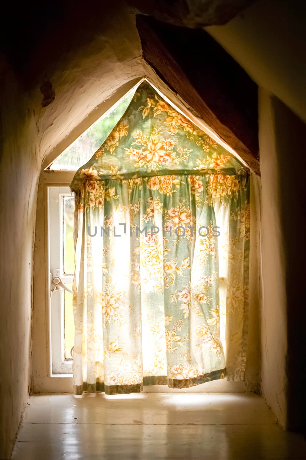 old cottage window with light creeping in behind the curtain