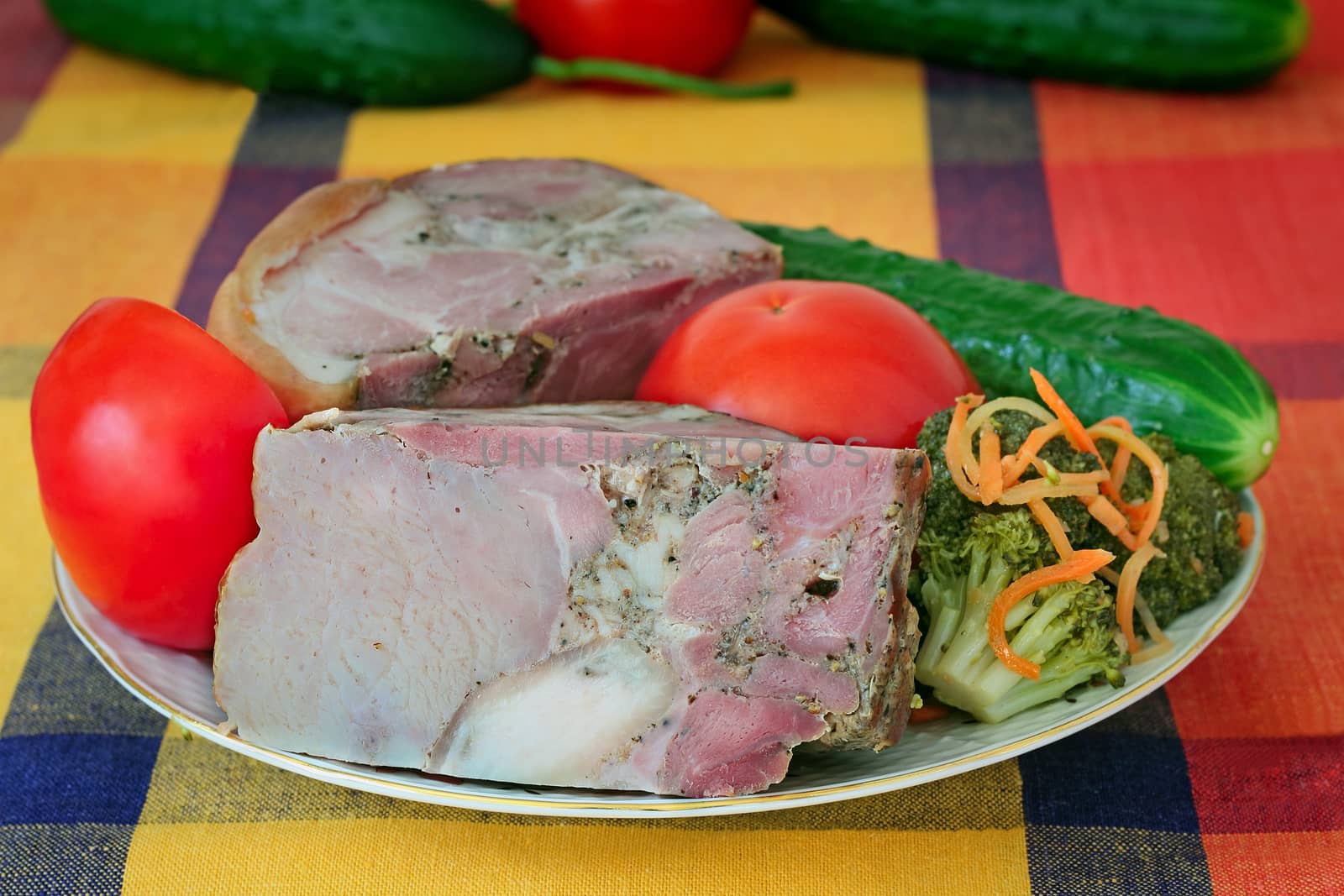 The big appetizing piece of smoked pork with vegetables is located on a table on a white plate.