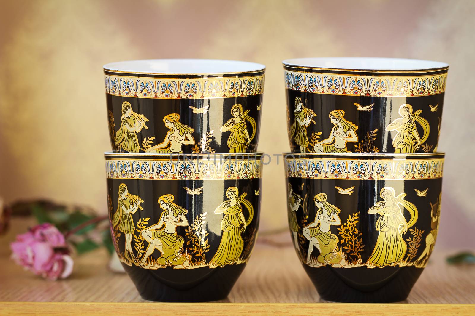 The beautiful tea cups decorated with a list with gold with the image of scenes from antique life.