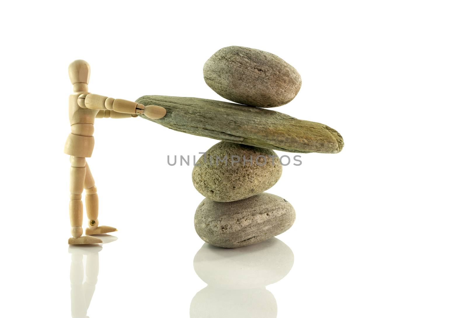 wooden puppet holding rocks isolated on white  in perfect balance