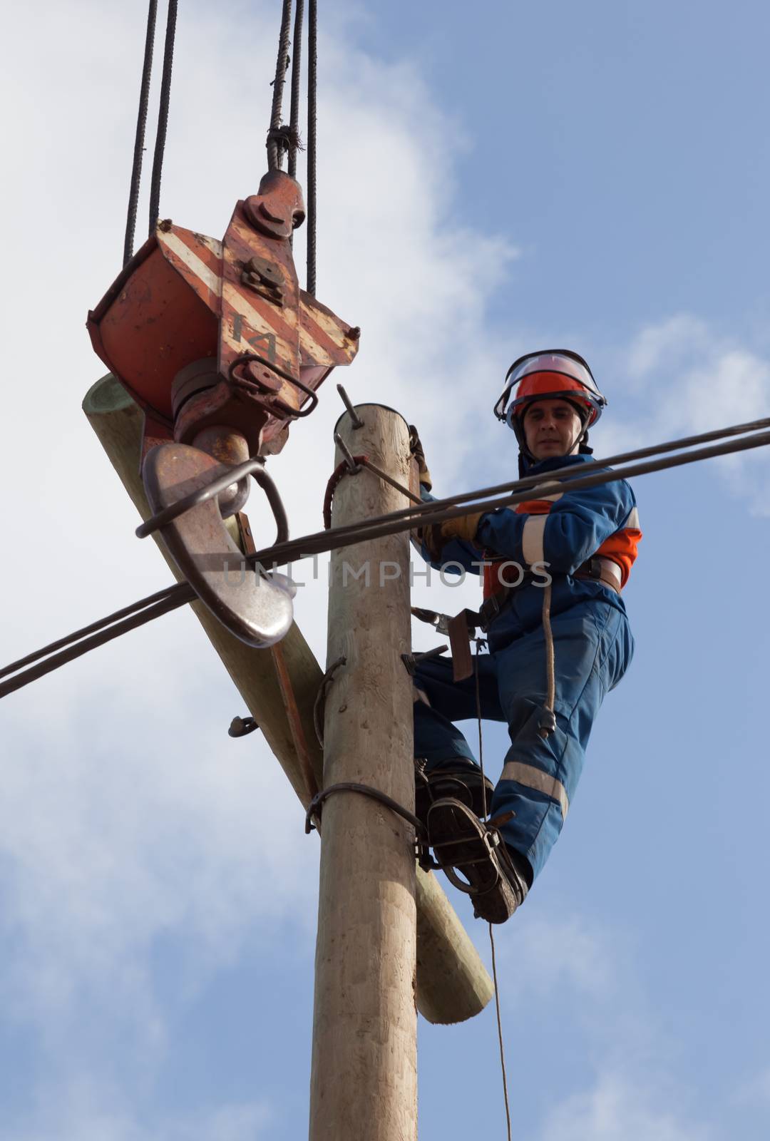 electrician raises the wire on top of an electricity pylon with the use of mobile crane