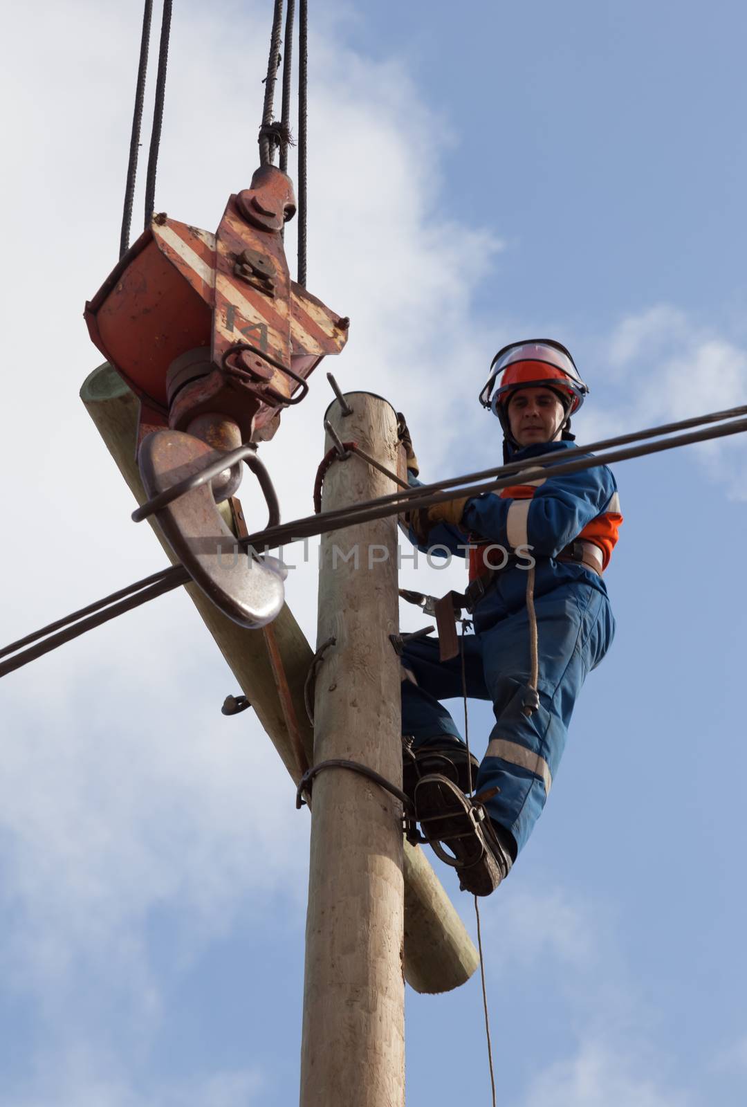 electrician raises the wire on top of an electricity pylon with the use of mobile crane 