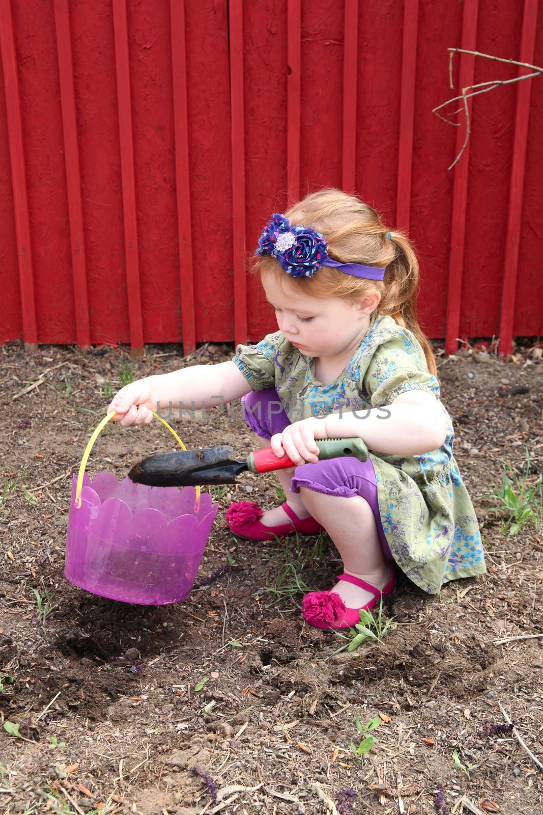 Little girl planting flowers in spring weather