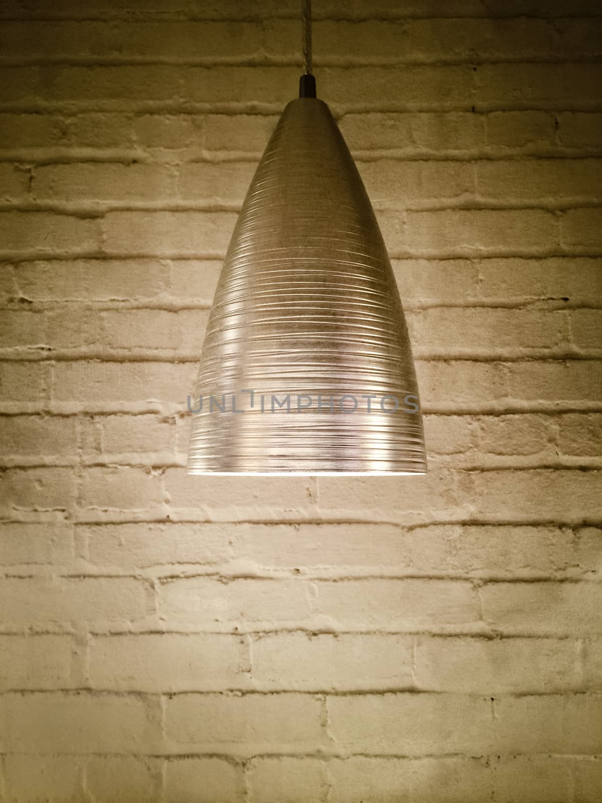 Modern metal lamp on brick wall background.