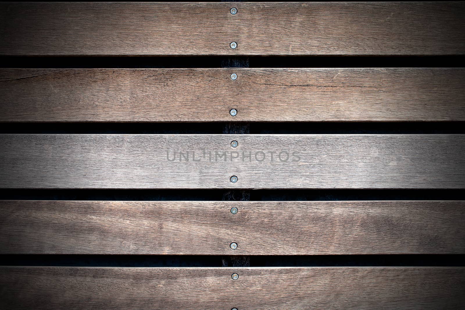 Wooden background with five brown and white boards and screws on black background