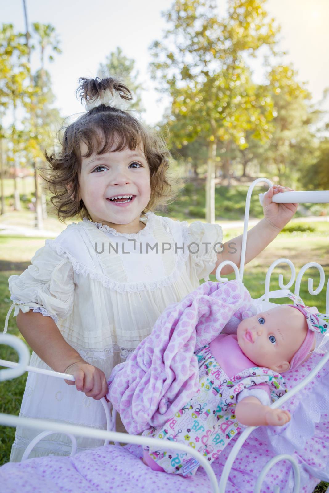 Adorable Young Baby Girl Playing with Her Baby Doll and Carriage Outdoors.