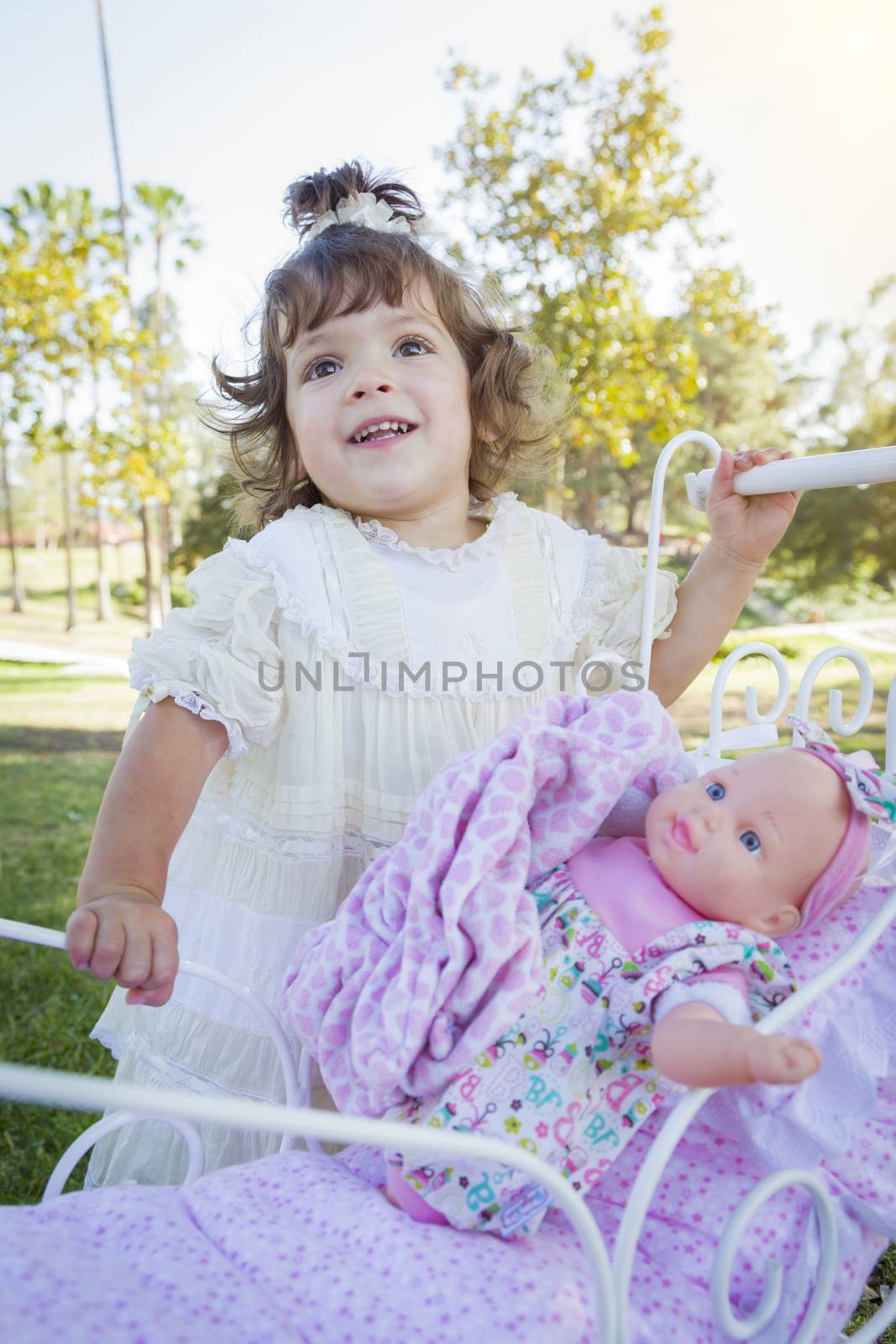 Adorable Young Baby Girl Playing with Her Baby Doll and Carriage Outdoors.