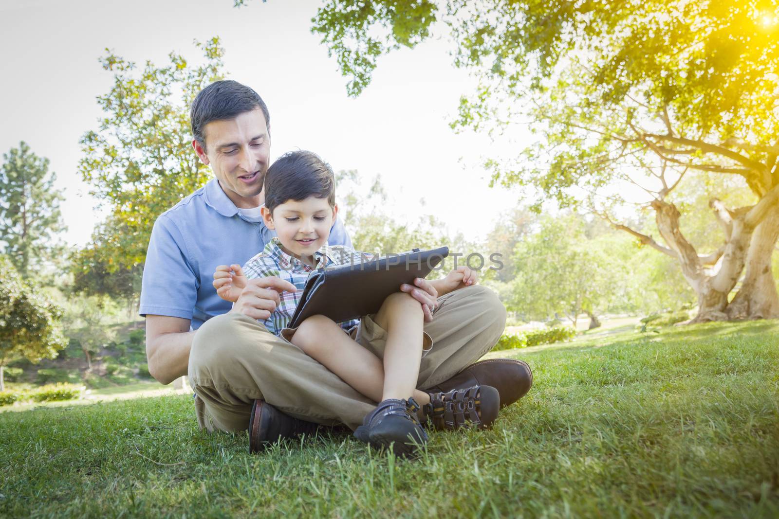 Handsome Mixed Race Father and Son Playing on Computer Tablet by Feverpitched