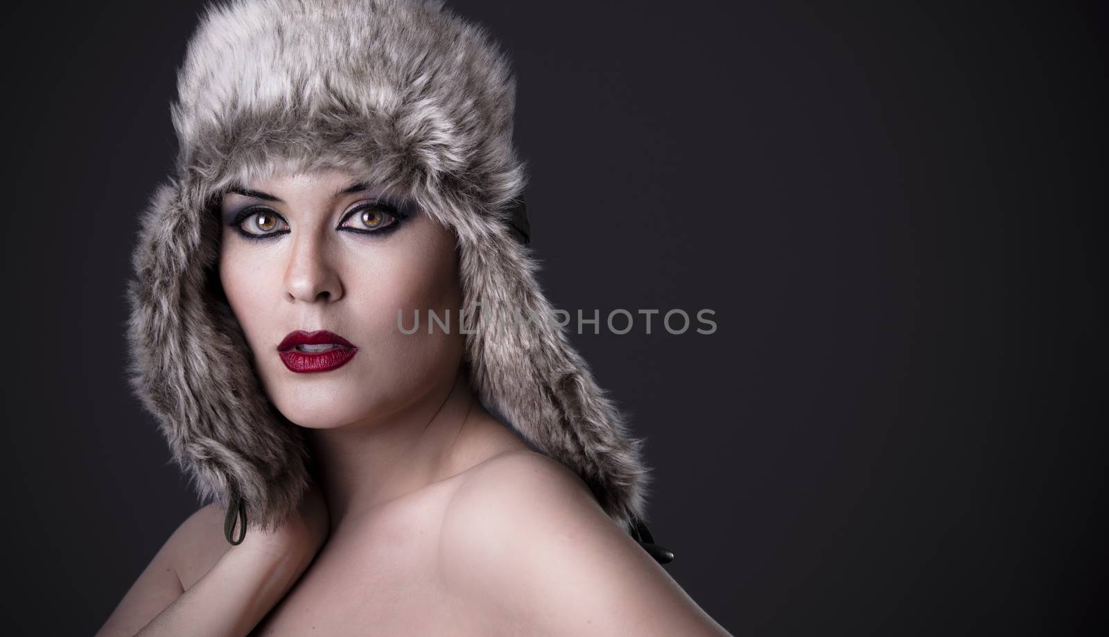 A sensual female green-eyed woman with fur hat, winter concept