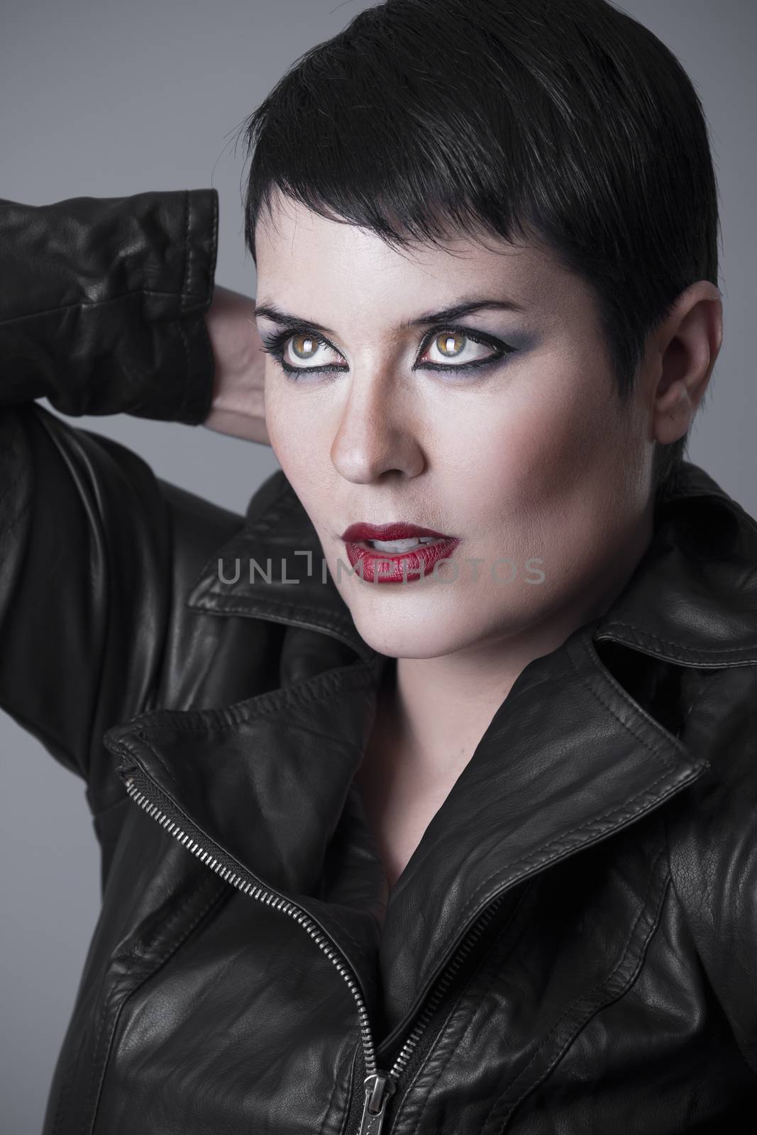 Beautiful sexy woman with black leather jacket on gray background